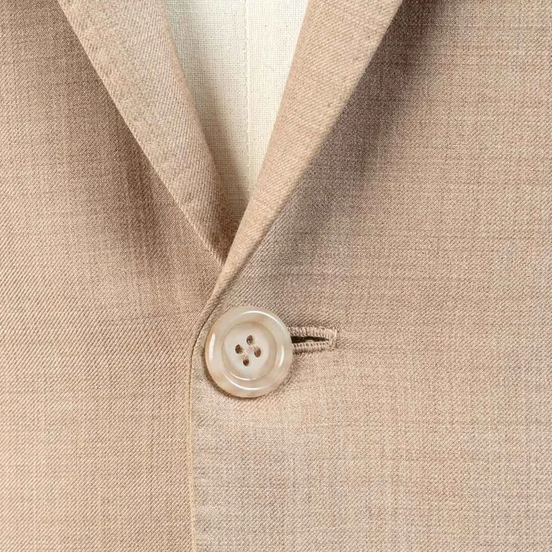 Close-up van parelmoeren knoop met handgestikte knoopsgat op zandkleurig bespoke zomer trouwpak, ambachtelijke afwerking
