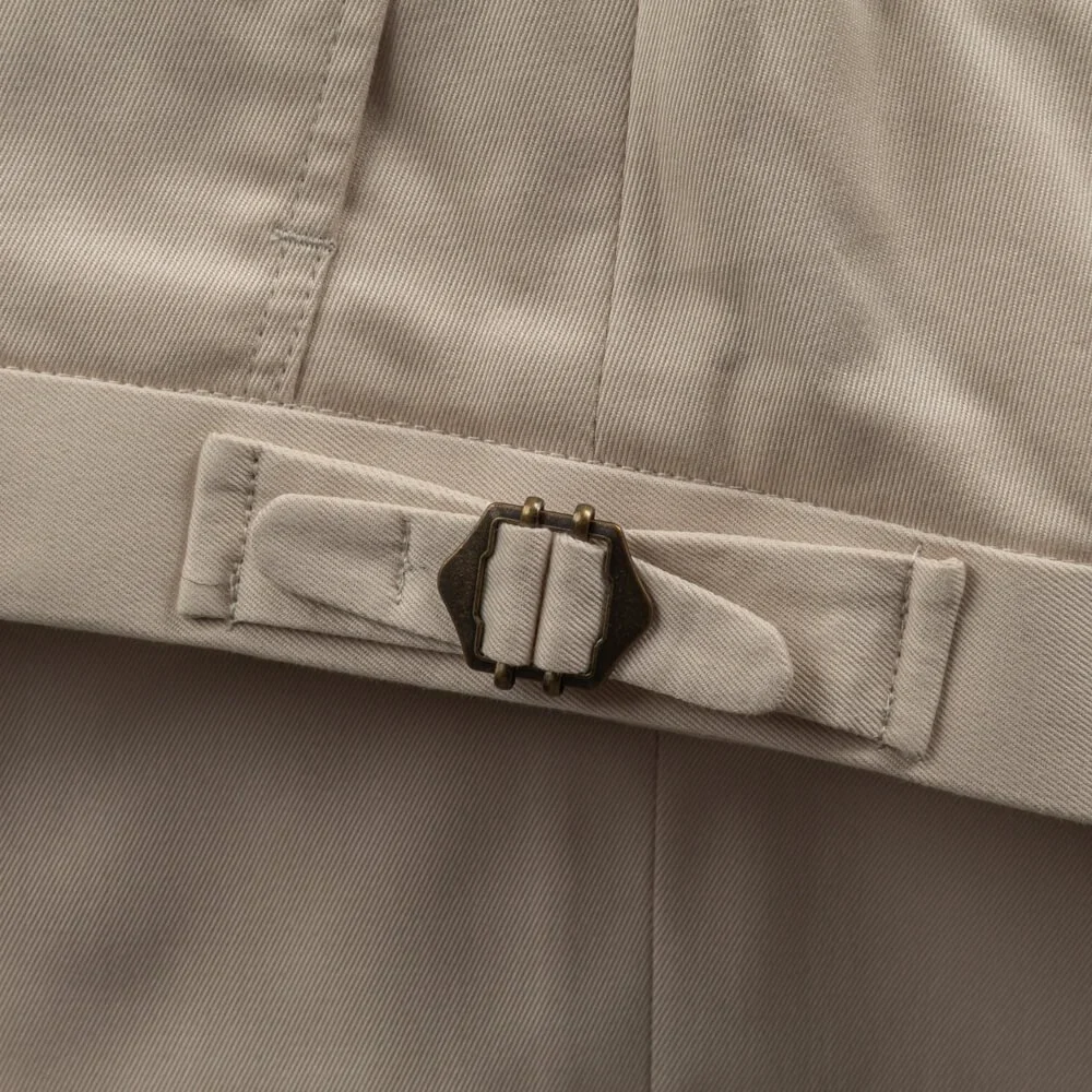 Detail zijtrekker op broekband van beige katoenen broek, elegante afwerking zonder riemlussen