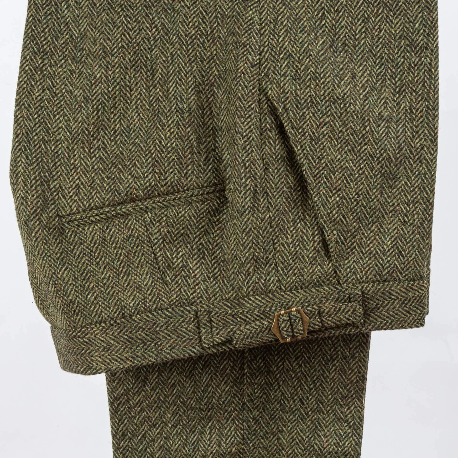 Olijfgroen tweed broek broekband detail met steekzak opening en zijtrekker buckle, visgraatpatroon textuur en ambachtelijke afwerking zichtbaar