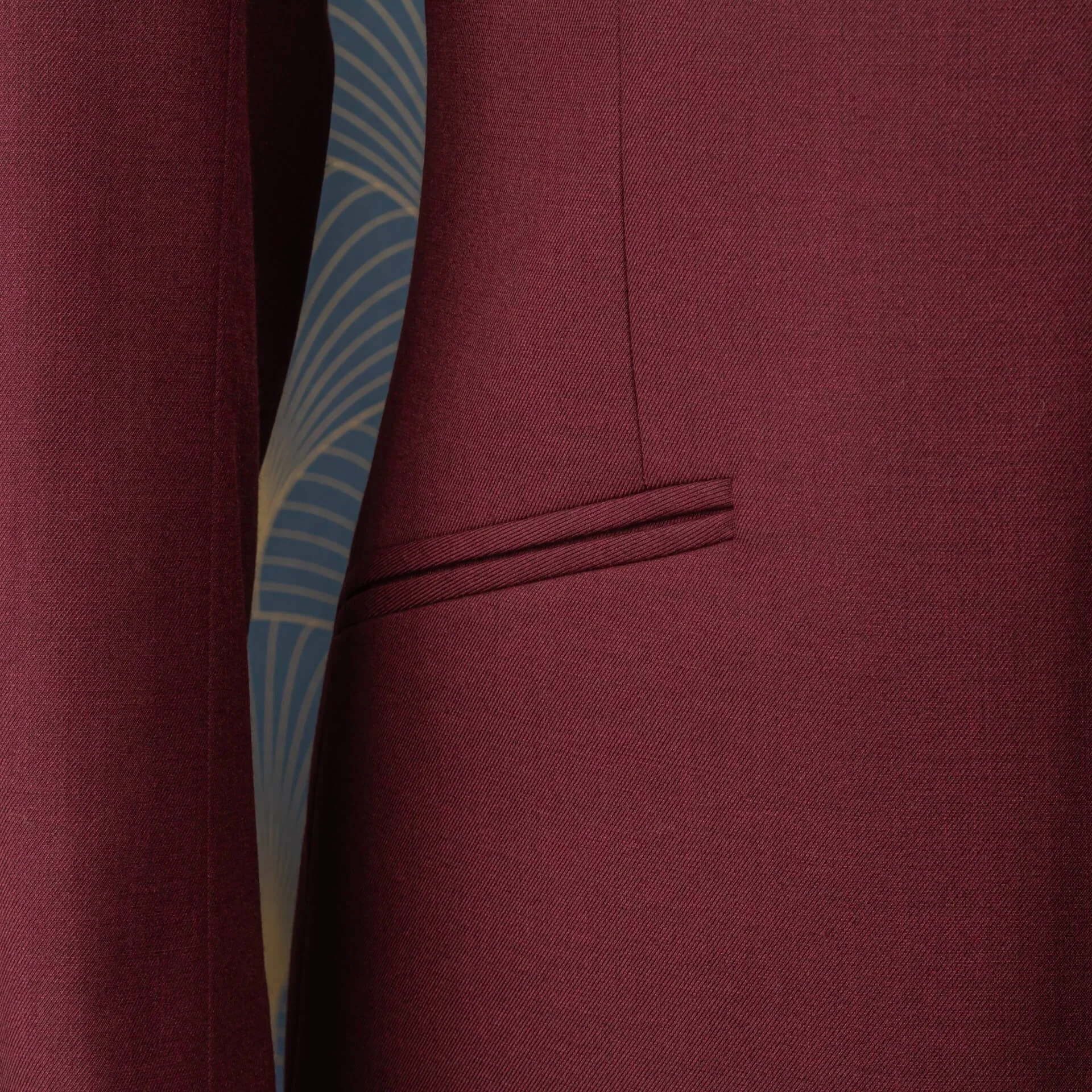 Schuine paspel zak detail bordeaux rood colbert met geometrisch voeringspatroon zichtbaar