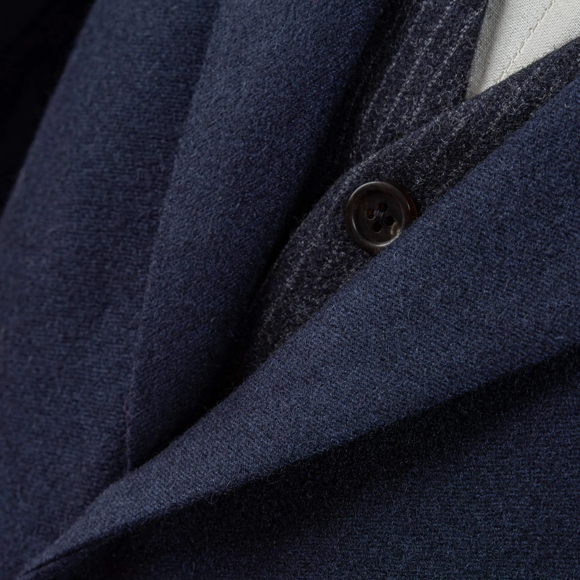 Close-up van notch lapel en hoornknoop op blue melange colbert, melange textuur in Fox Brothers merinowol zichtbaar