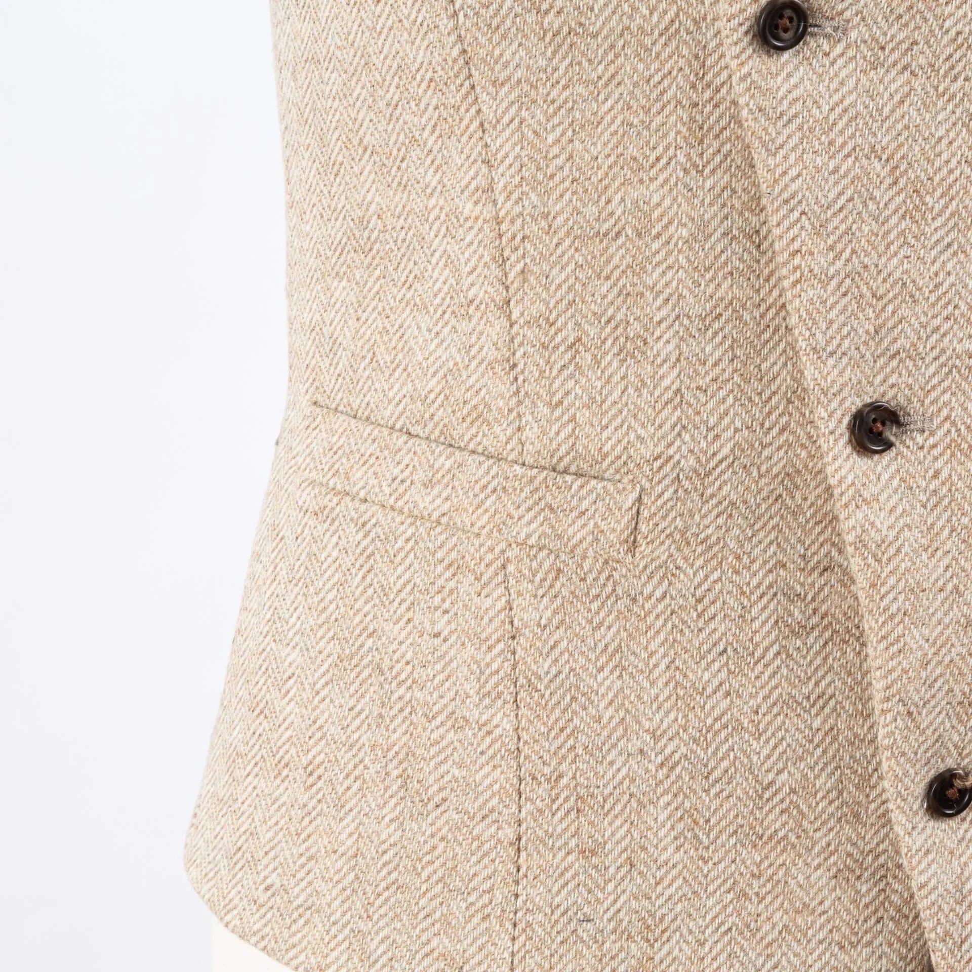Zijkant light sand herringbone gilet met paspelzakken en bruine hoornen knopen