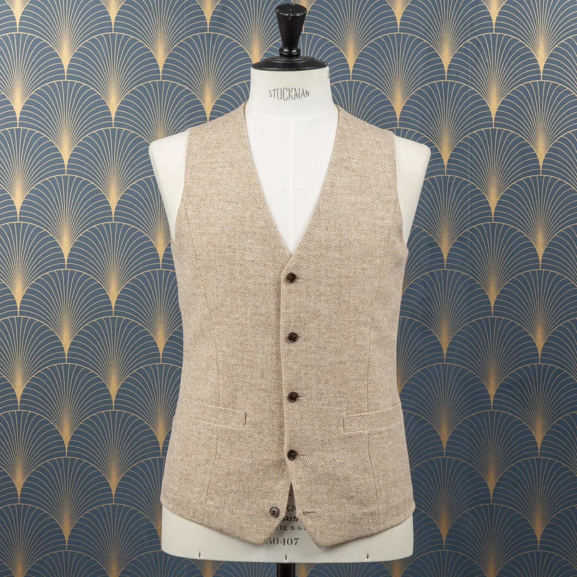 Close-up van goudkleurige voering in saffiergroen colbert met paspelzakken en donkerbruine hoornen knopen, toont vakmanschap van binnenafwerking en light sand tweed gilet