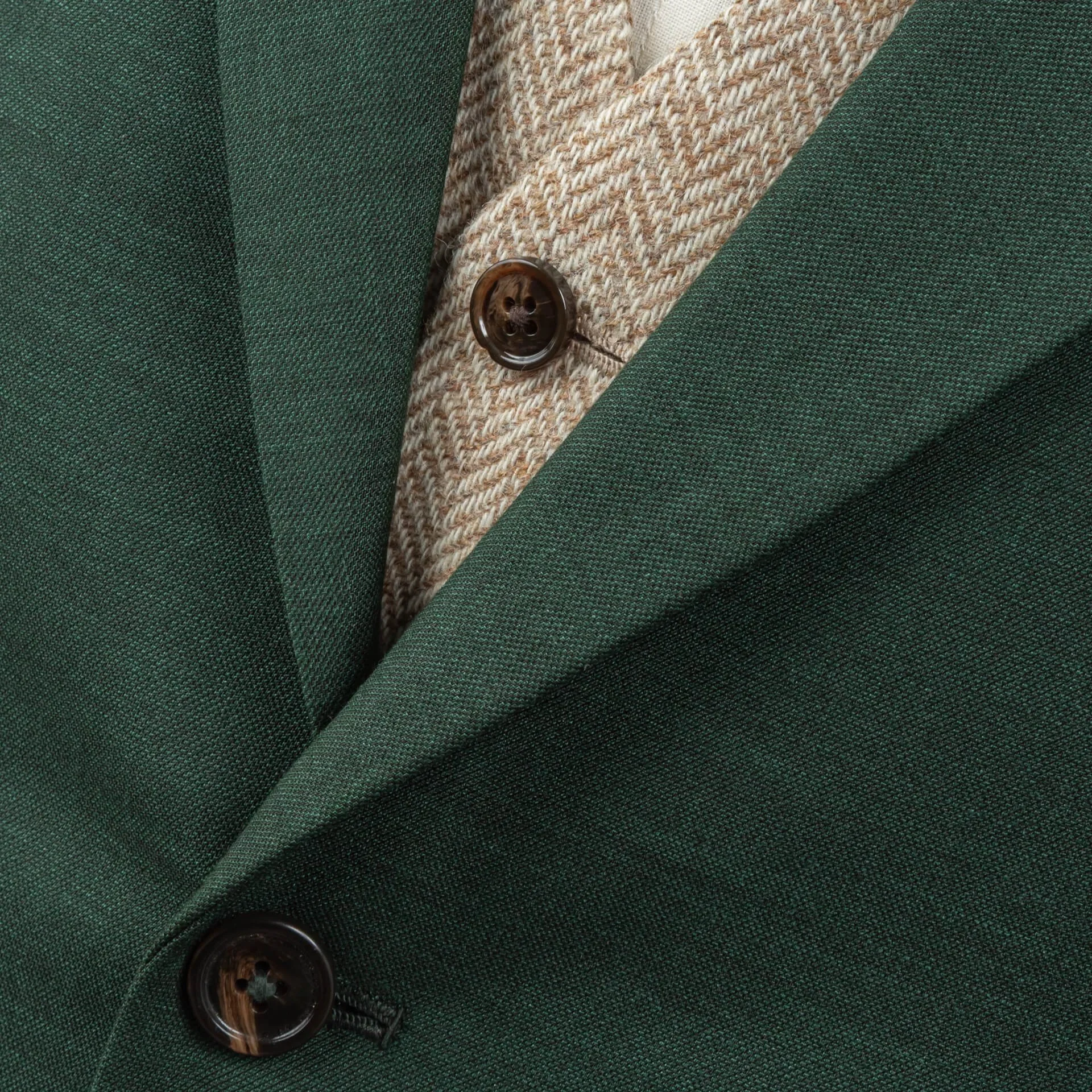 Close-up van saffiergroen merino wol colbert gecombineerd met light sand herringbone tweed gilet, toont het contrast tussen gladde sharkskin en robuuste tweed textuur met donkerbruine hoornen knopen