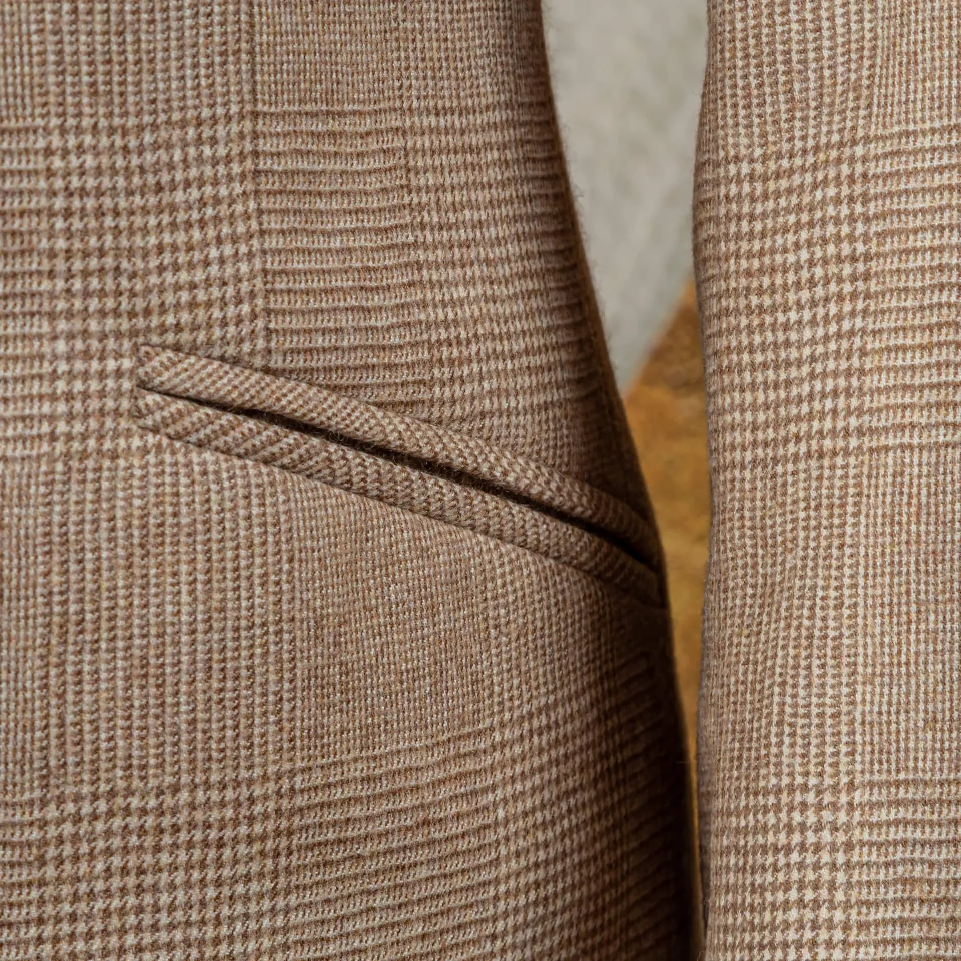 Close-up van schuine paspelzak op camel check flannel colbert