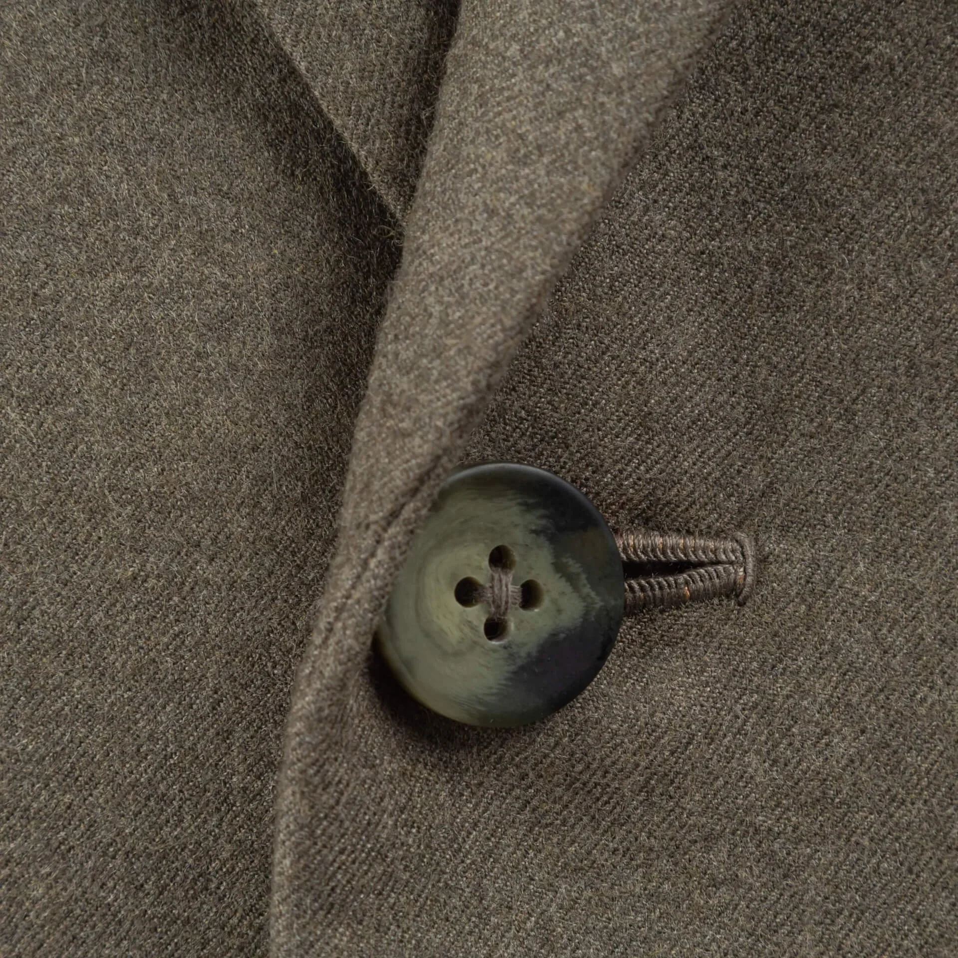 Detailfoto van knoop met subtiele groen-grijze marmerering op oatmeal flannel colbert met handgemaakt knoopsgat