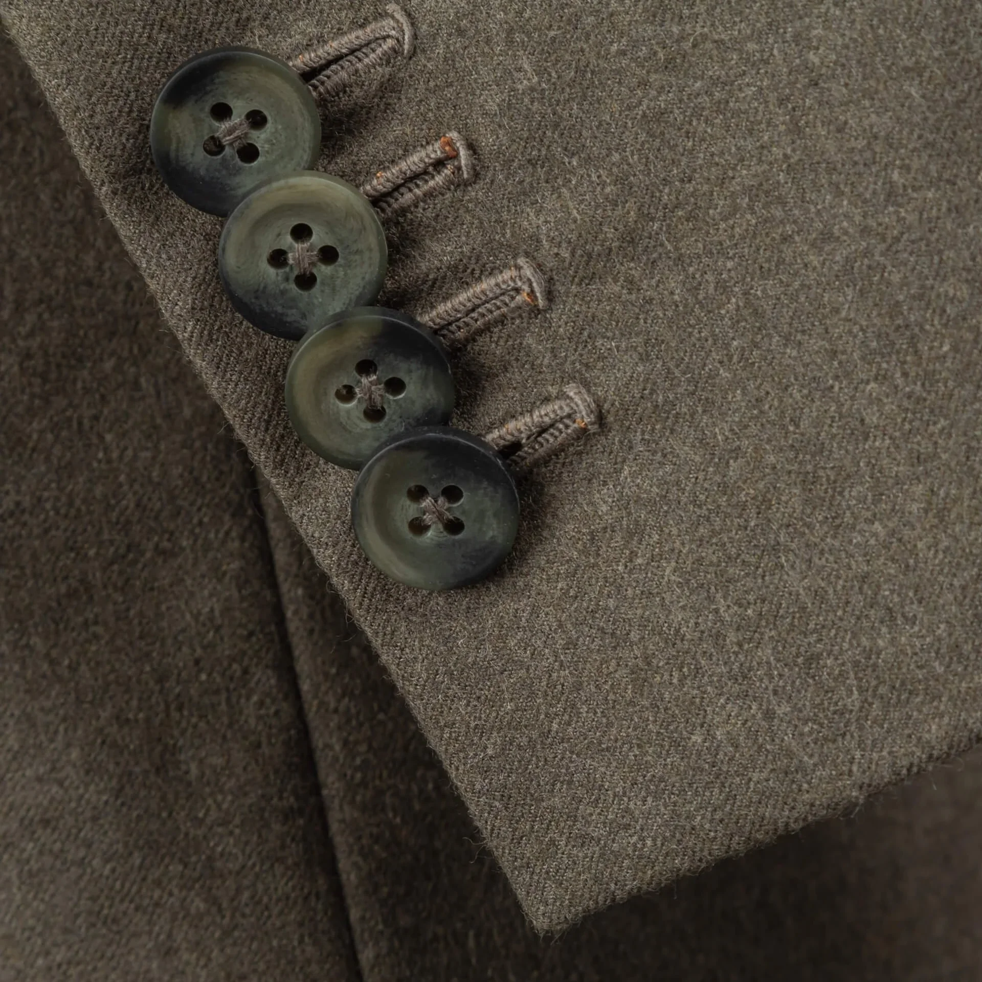 Drie mouwknopen met groen-grijze marmerering op oatmeal flannel mouw, functionele knoopsgaten