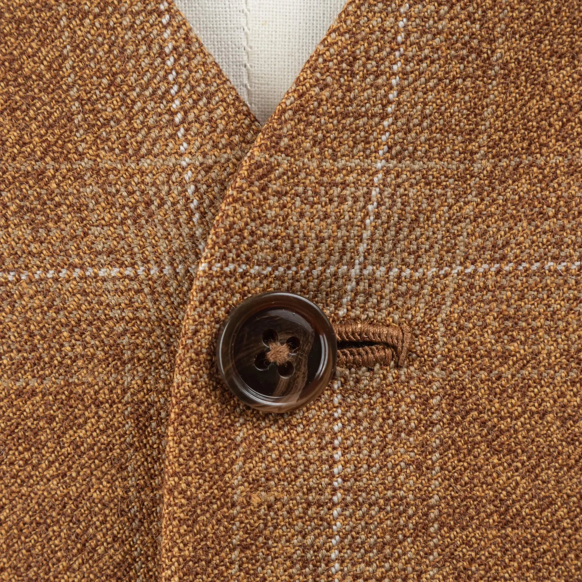 Extreme close-up van fawn tweed weefsel met windowpane ruit en bruine hoornen knoop met handgemaakt knoopsgat