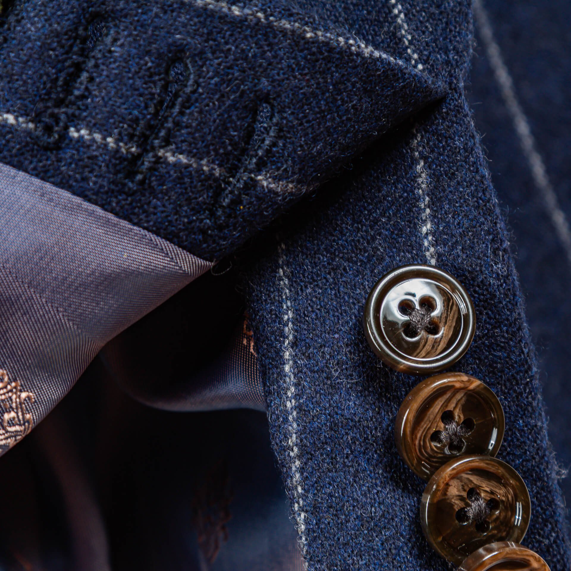 Detail van mouwknopen met zichtbare zijden voering met paisley motief op navy krijtstreep maatcolbert