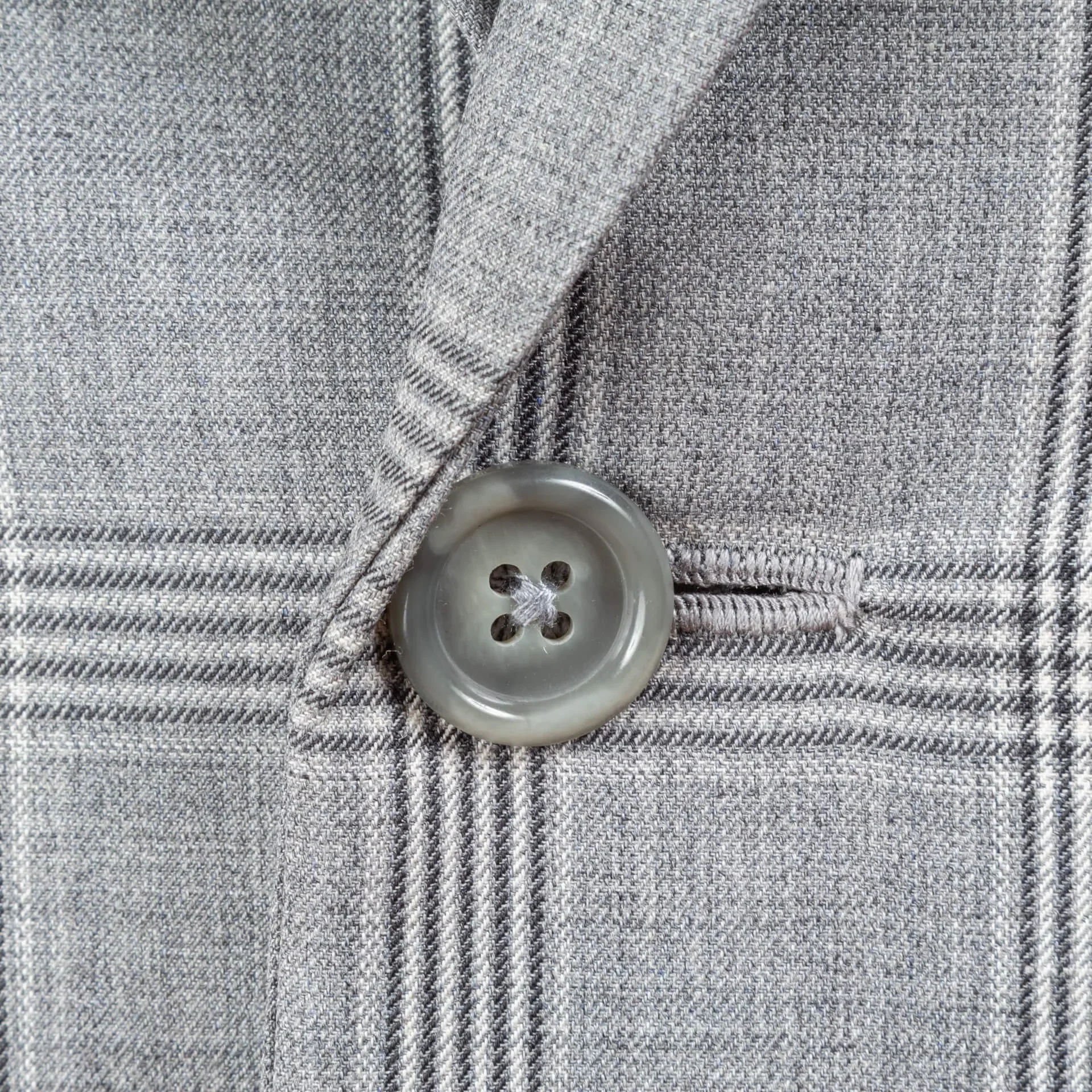 Macro-opname van grijze hoornen frontknoop met handgestikt knoopsgat