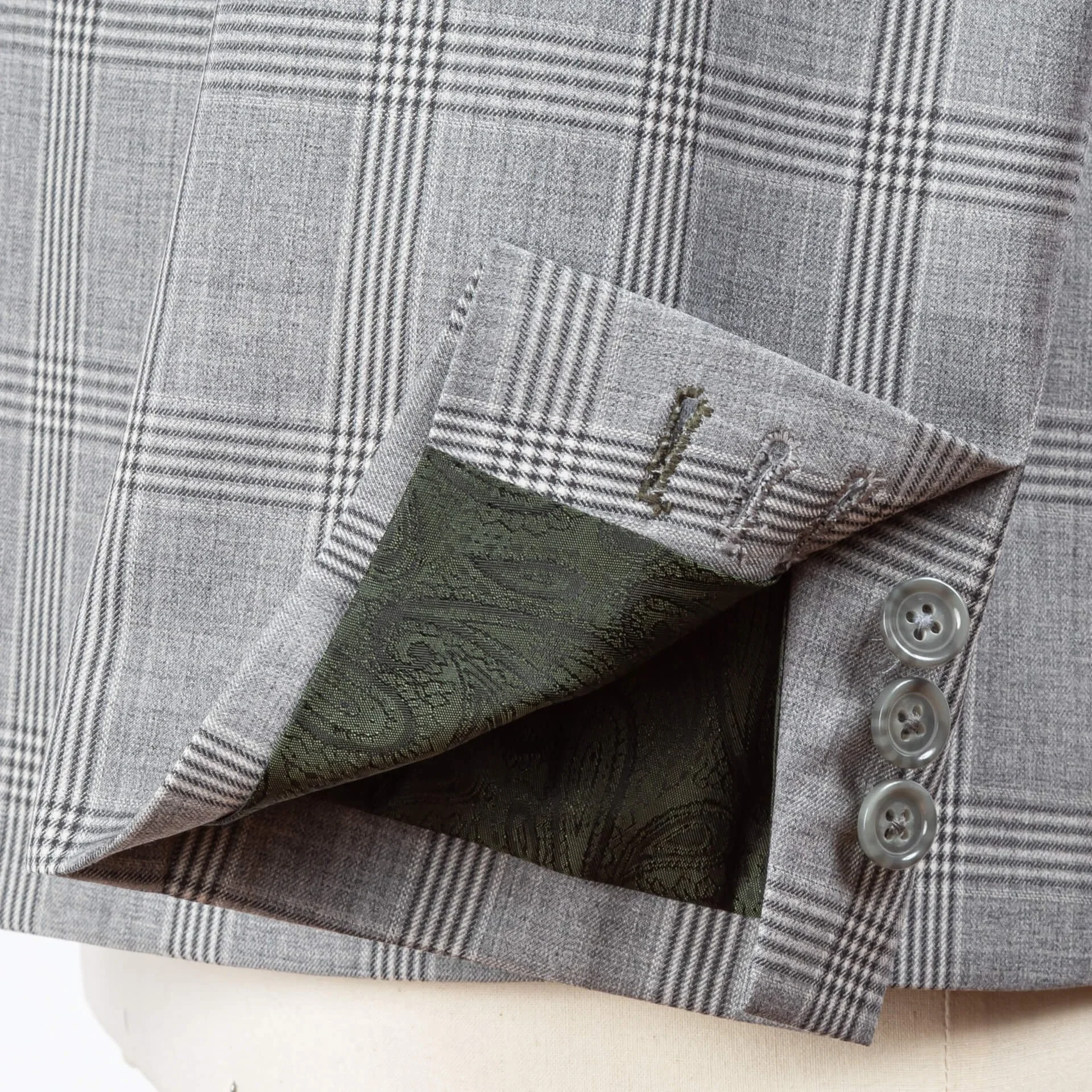 Omgeslagen mouw toont donkergroene zijden voering met paisley motief