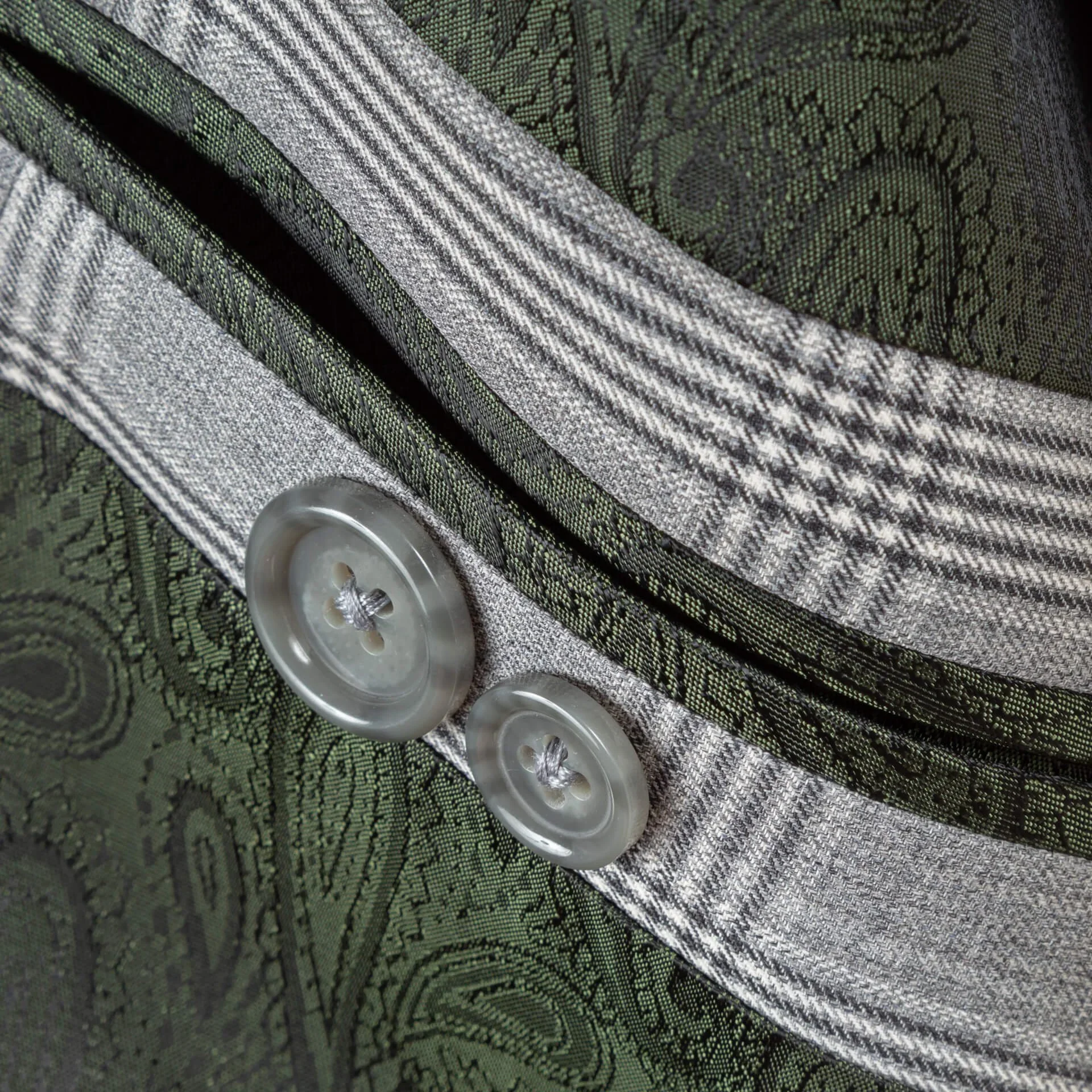 Close-up van groene paisley zijden voering met grijze reserveknopen