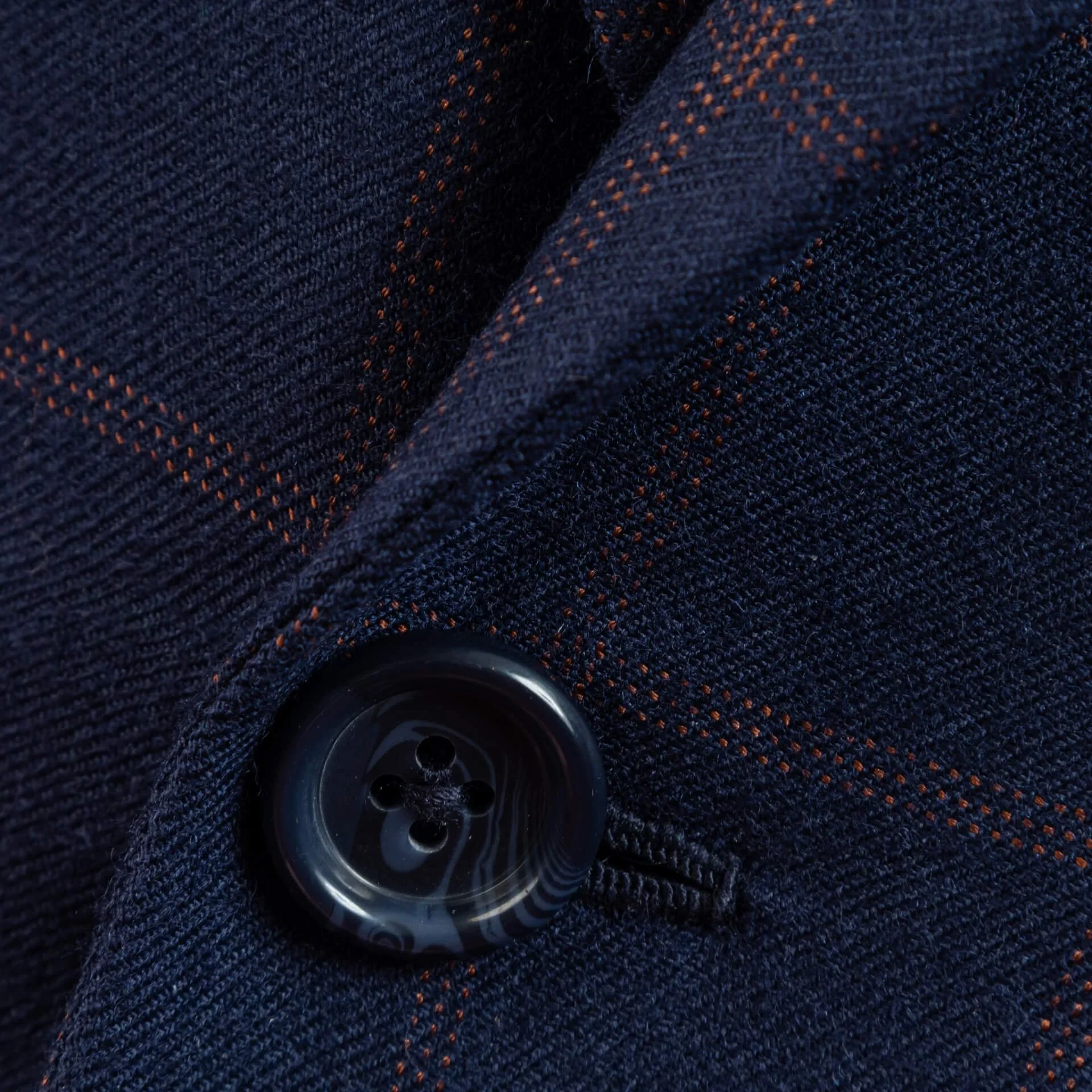 Close-up van donkere hoornen knoop op navy flanel met beaded oranje windowpane, handgemaakte afwerking