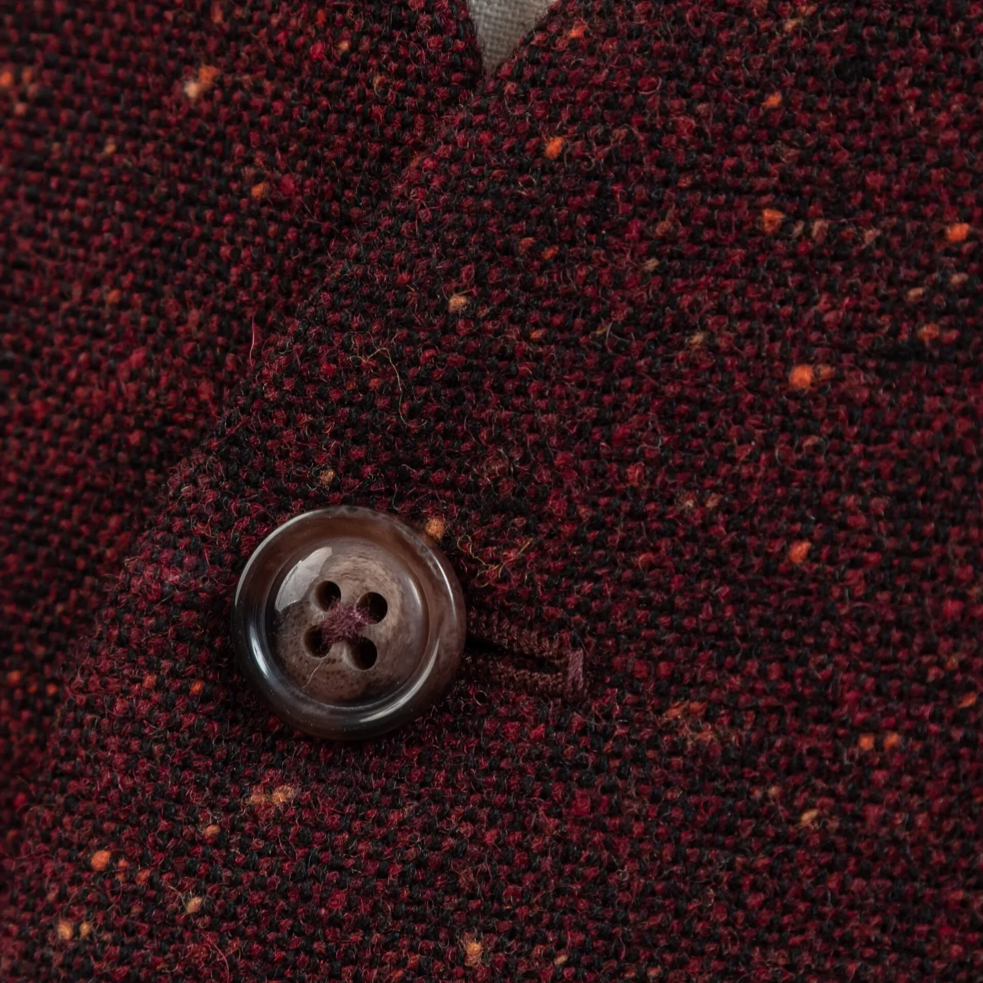 Extreme close-up van burgundy Donegal tweed met kleurrijke knaps en bruine hoornen knoop