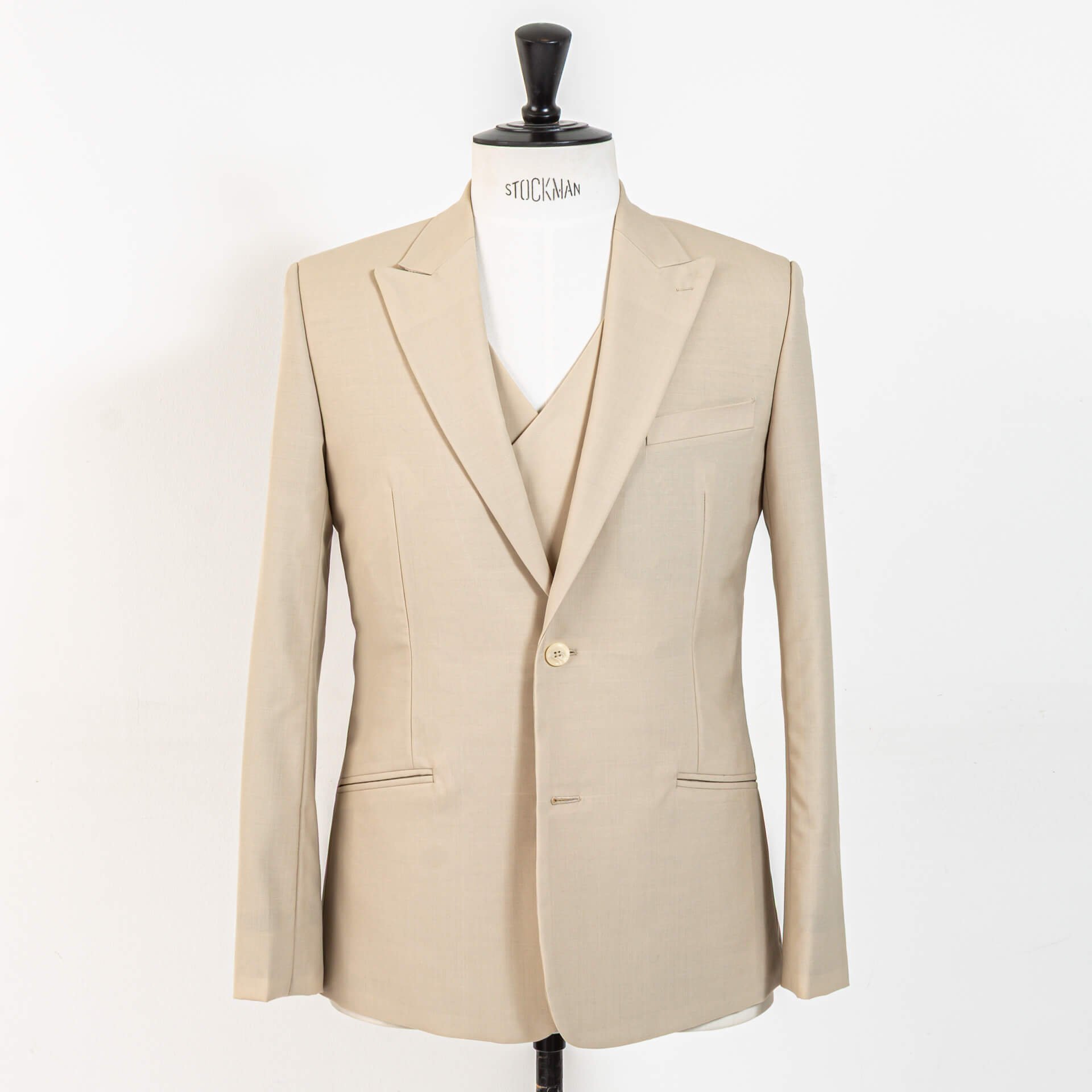 Driedelig bespoke trouwpak in biscuit kleurige wol, 2-knoops colbert met peak lapels en schuine paspelzakken over double-breasted 4x2 gilet, gepresenteerd op Stockman paspop