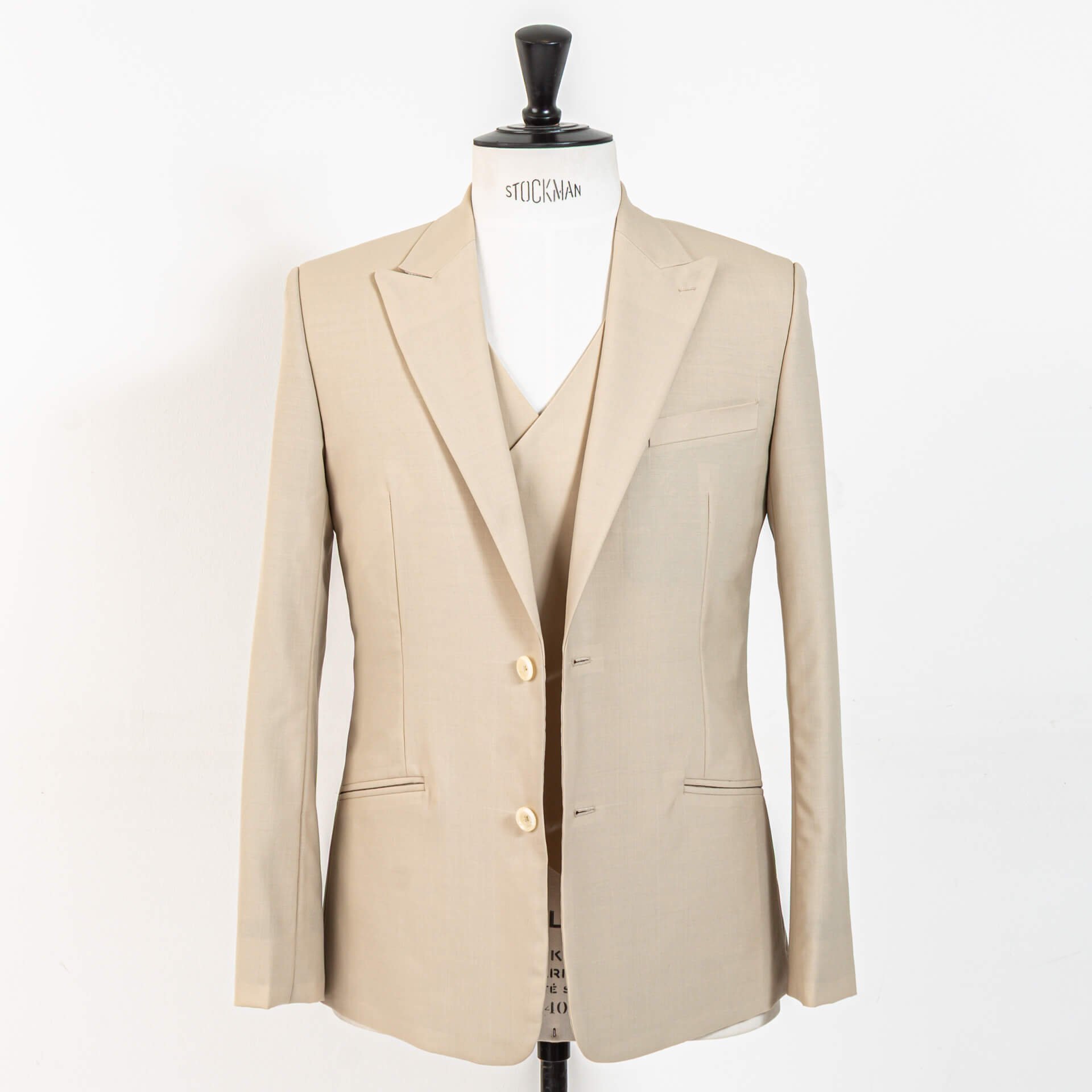 Driedelig bespoke trouwpak in biscuit wol met open colbert, double-breasted gilet zichtbaar, 1-knoops jasje met peak lapels en schuine paspelzakken op Stockman paspop