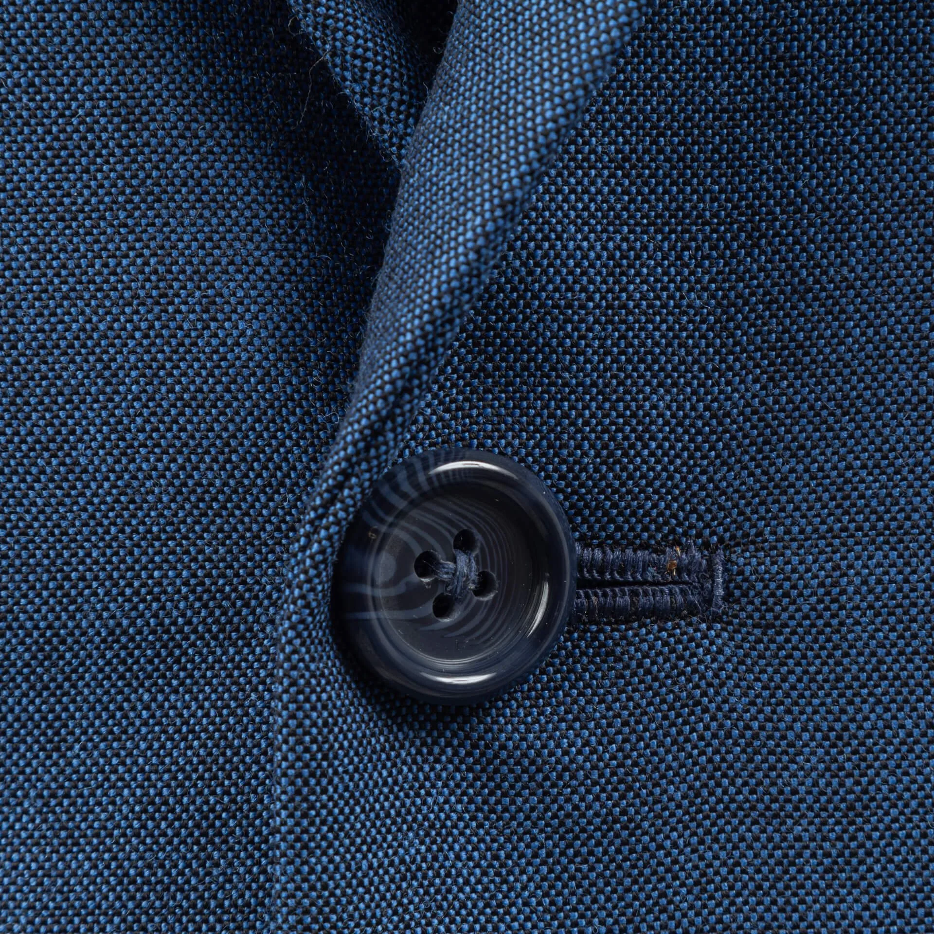 Close-up van handgestikt knoopsgat met hoornknoop op blauw colbert