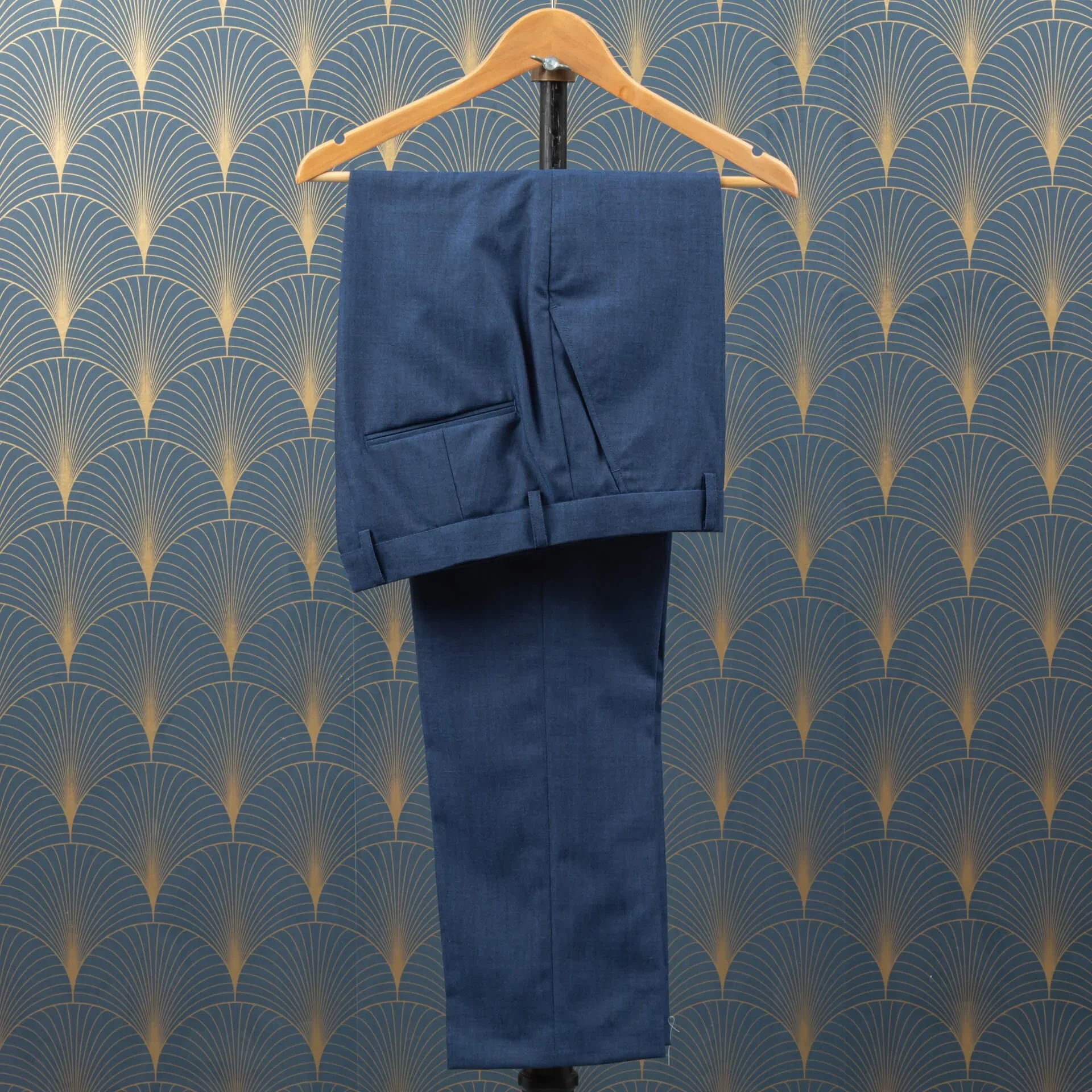 Blauwe maatbroek in Crispaire wol met riemlussen en omslag op houten kledinghouder