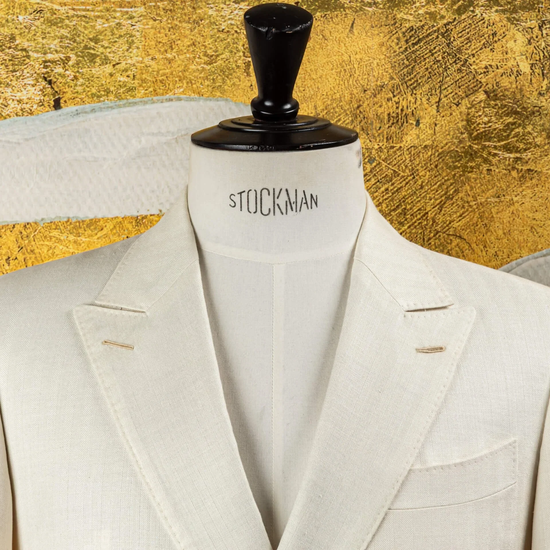 Close-up van de peak lapels met handgemaakte Milanese knoopsgaten op een off-white double-breasted trouwpak.