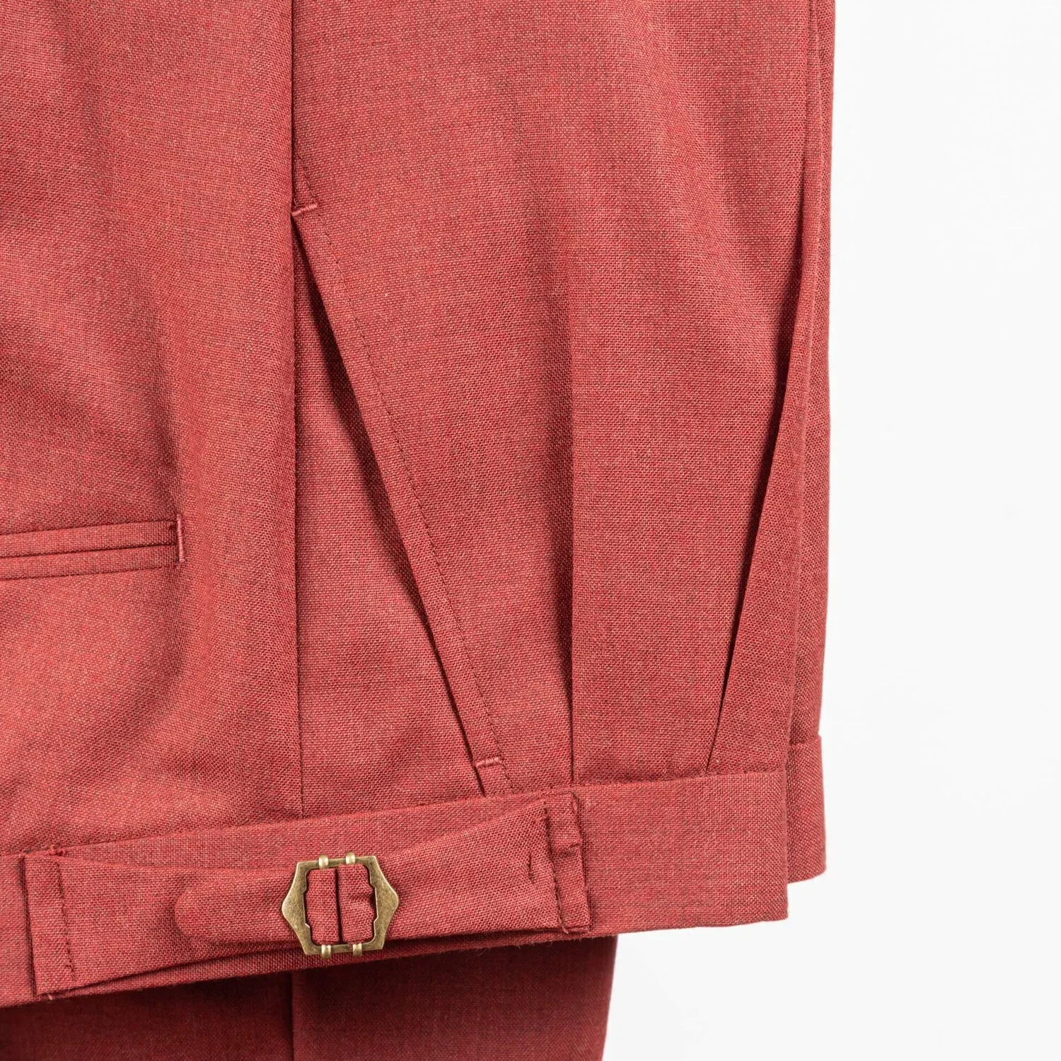 Close-up van de bronzen side adjuster gesp op de terracotta broek op maat met dubbele bandplooi.