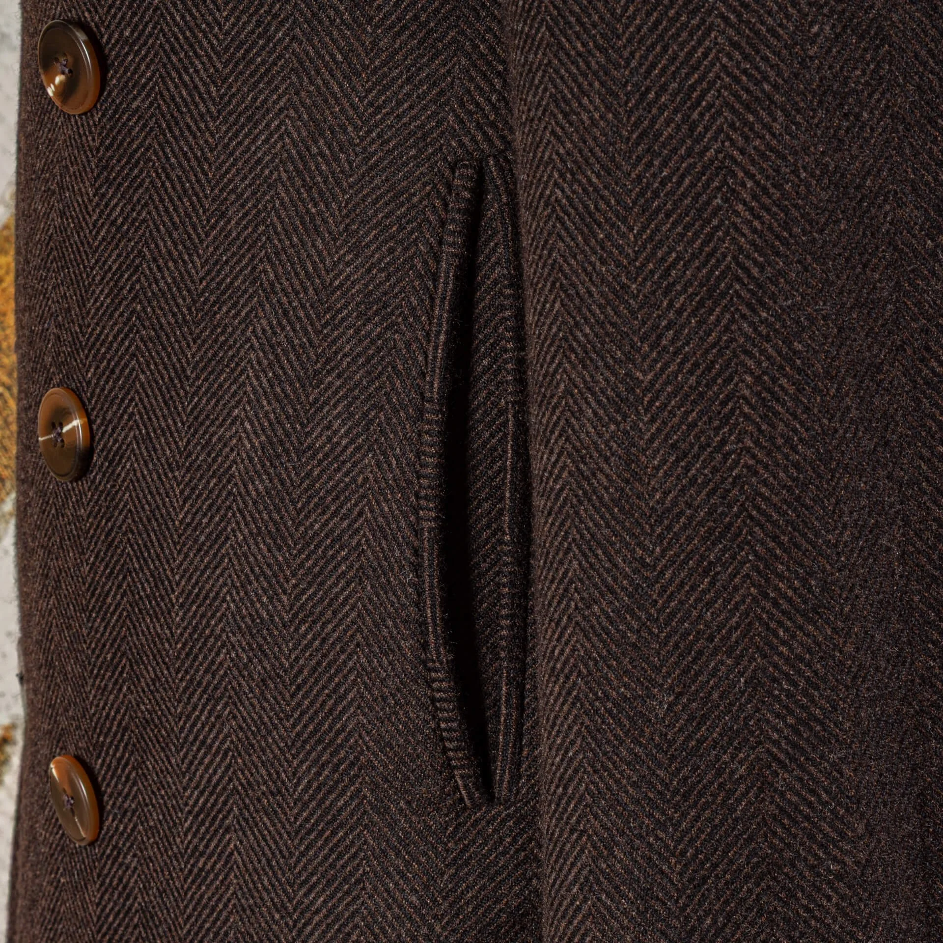 Paspelzak close-up op chocolate brown herringbone peacoat