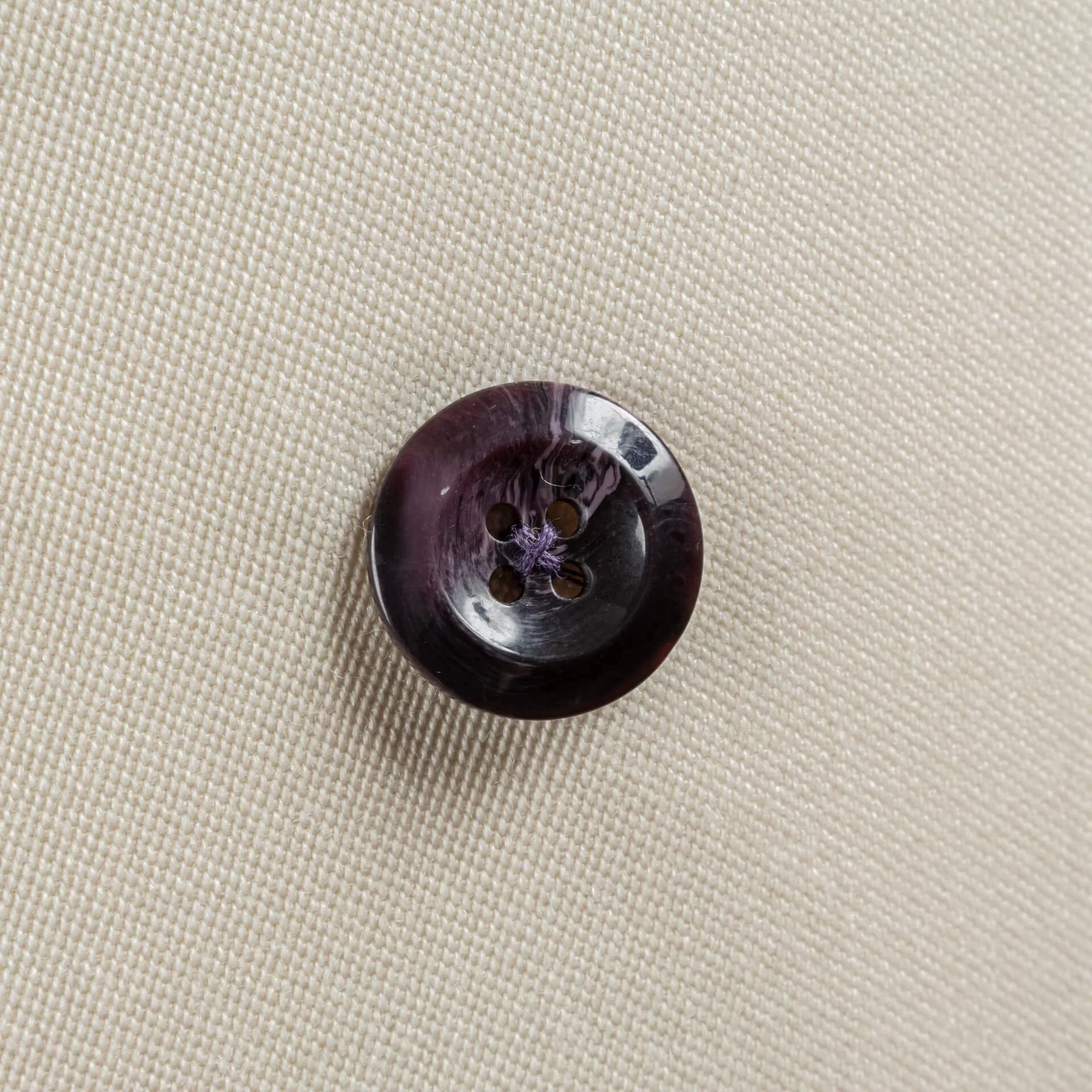 Close-up van de witte barathea-weving met een donkere knoop met paarse nerf op de revers-overlap van een 4x1 double-breasted jasje, trouwpak op maat in Holland & Sherry Black Tie barathea van 370 gram