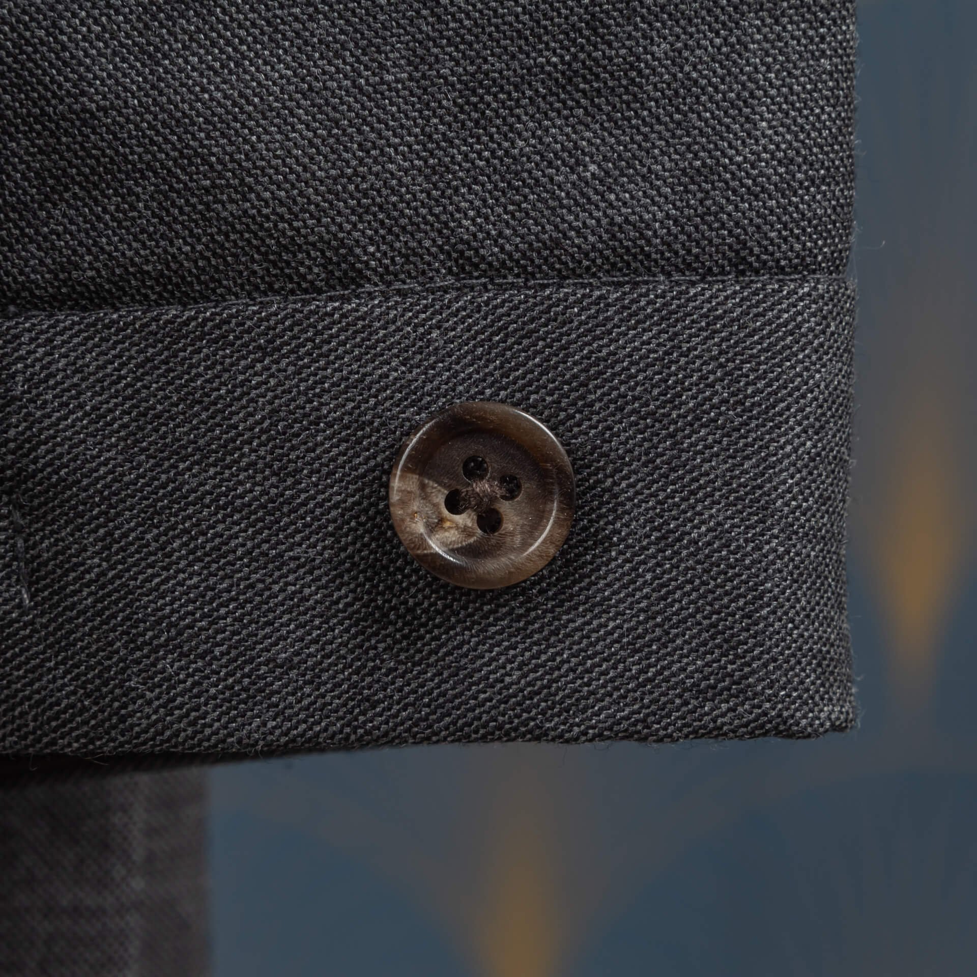 Knoop van bruin hoorn op de broekband van een grijze sharkskin pak broek