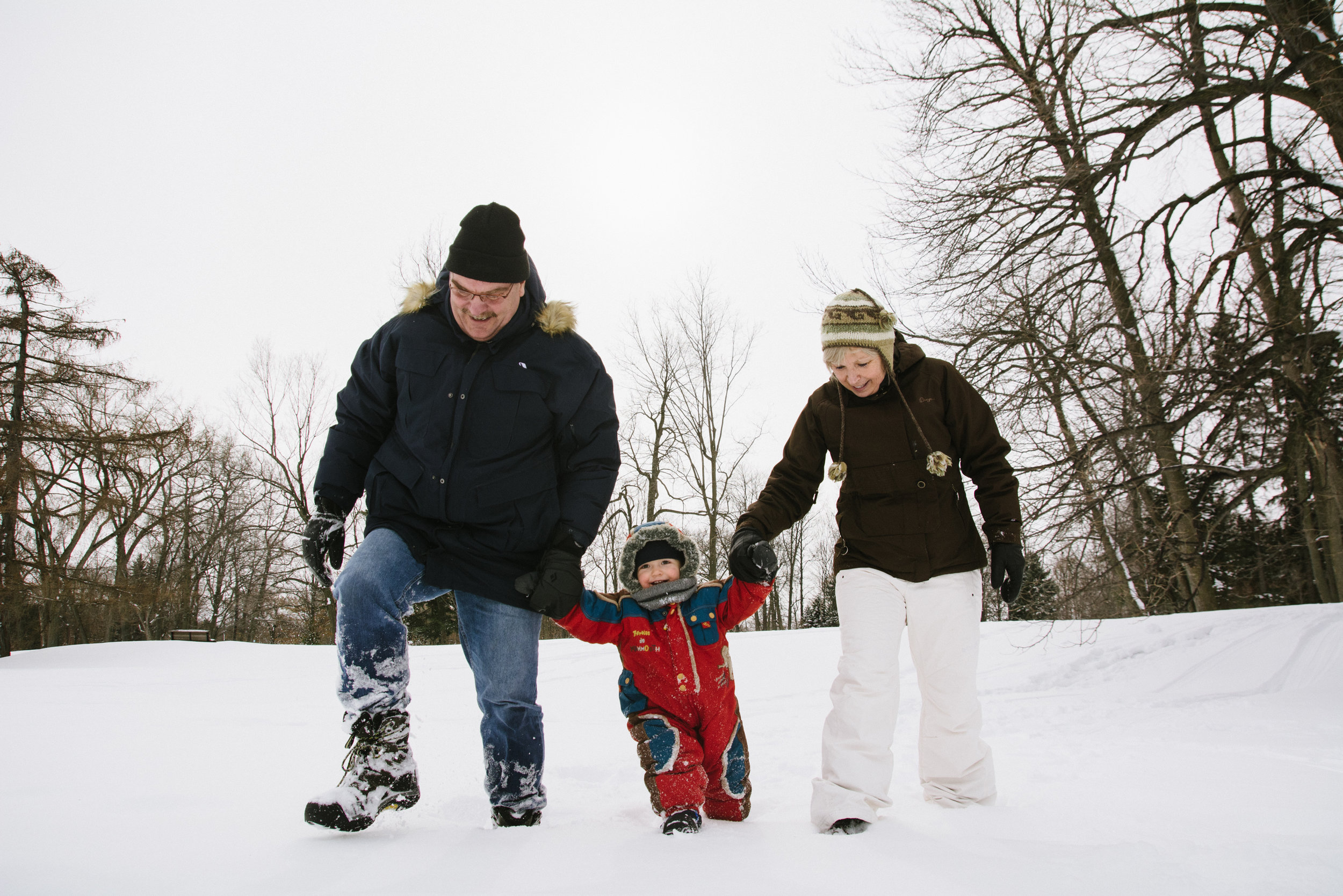 photo-d-un-enfant-en-habit-de-neige-avec-ses-grands-parents-l-hiver-a-montreal-photographe-enfant-famille-montreal.jpg