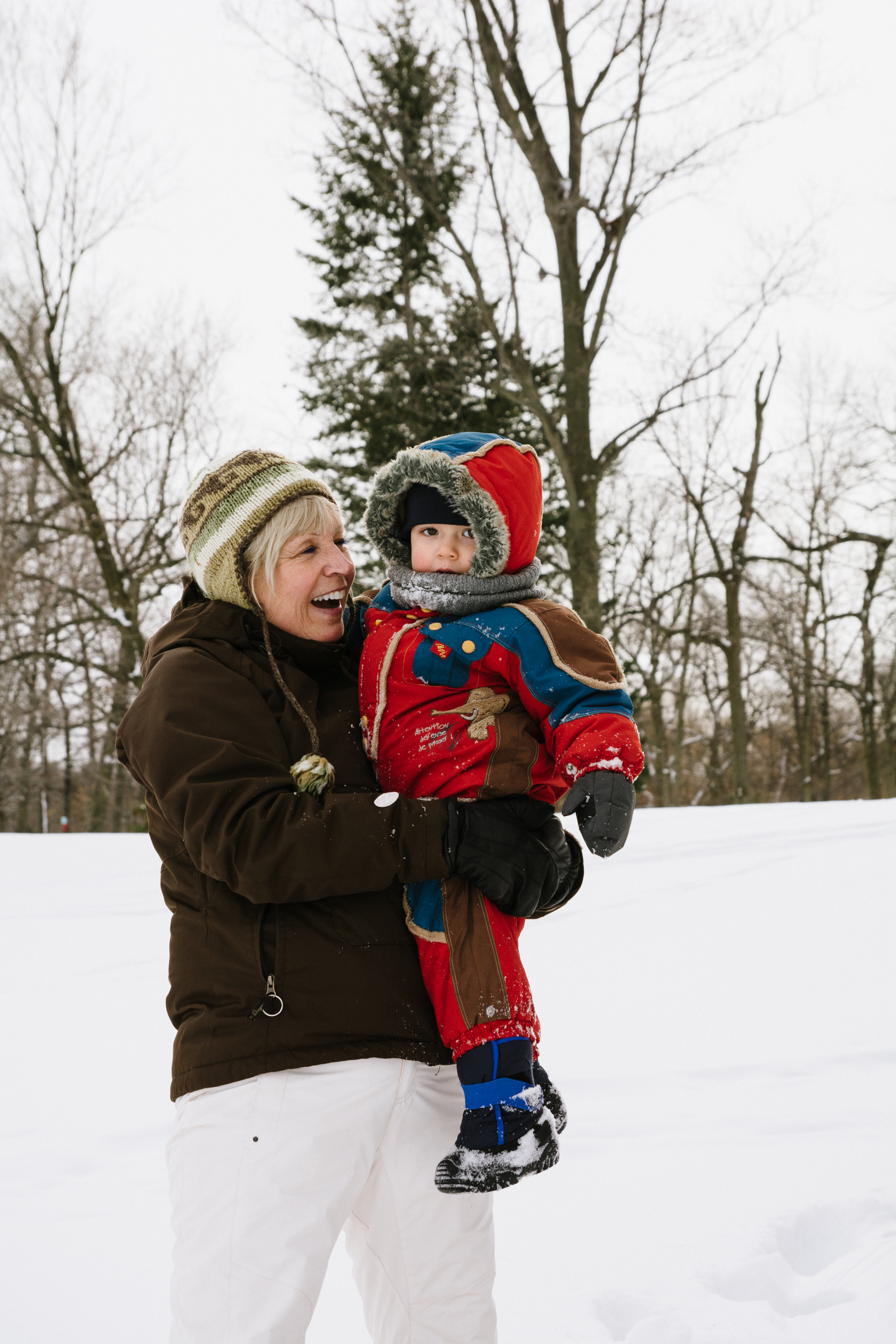 photo-d-une-grand-mere-avec-un-enfant-en-habit-de-neige-dans-les-bras-l-hiver-a-montreal-photographe-enfant-famille-montreal-2.jpg
