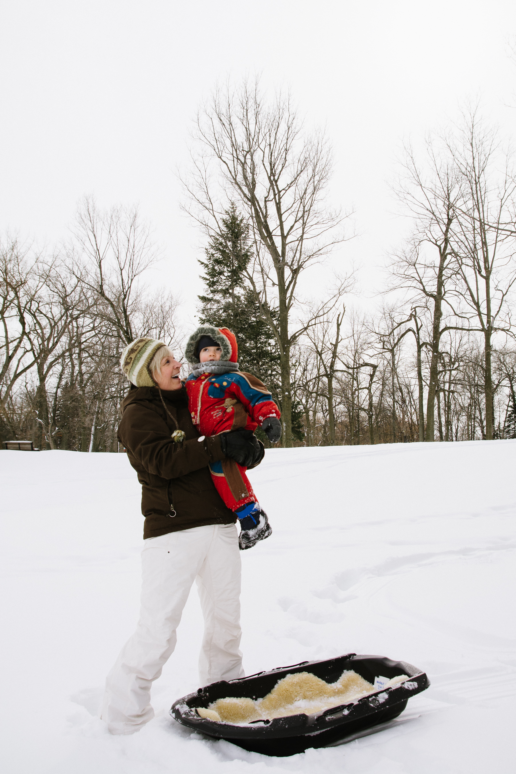 photo-d-une-grand-mere-avec-un-enfant-en-habit-de-neige-dans-les-bras-l-hiver-a-montreal-photographe-enfant-famille-montreal.jpg