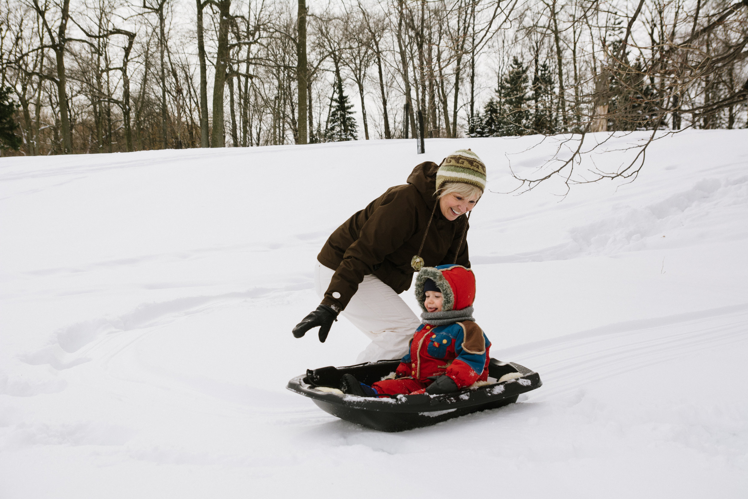 photo-d-une-grand-mere-avec-un-enfant-qui-glisse-en-traineau-l-hiver-a-montreal-photographe-enfant-famille-montreal.jpg