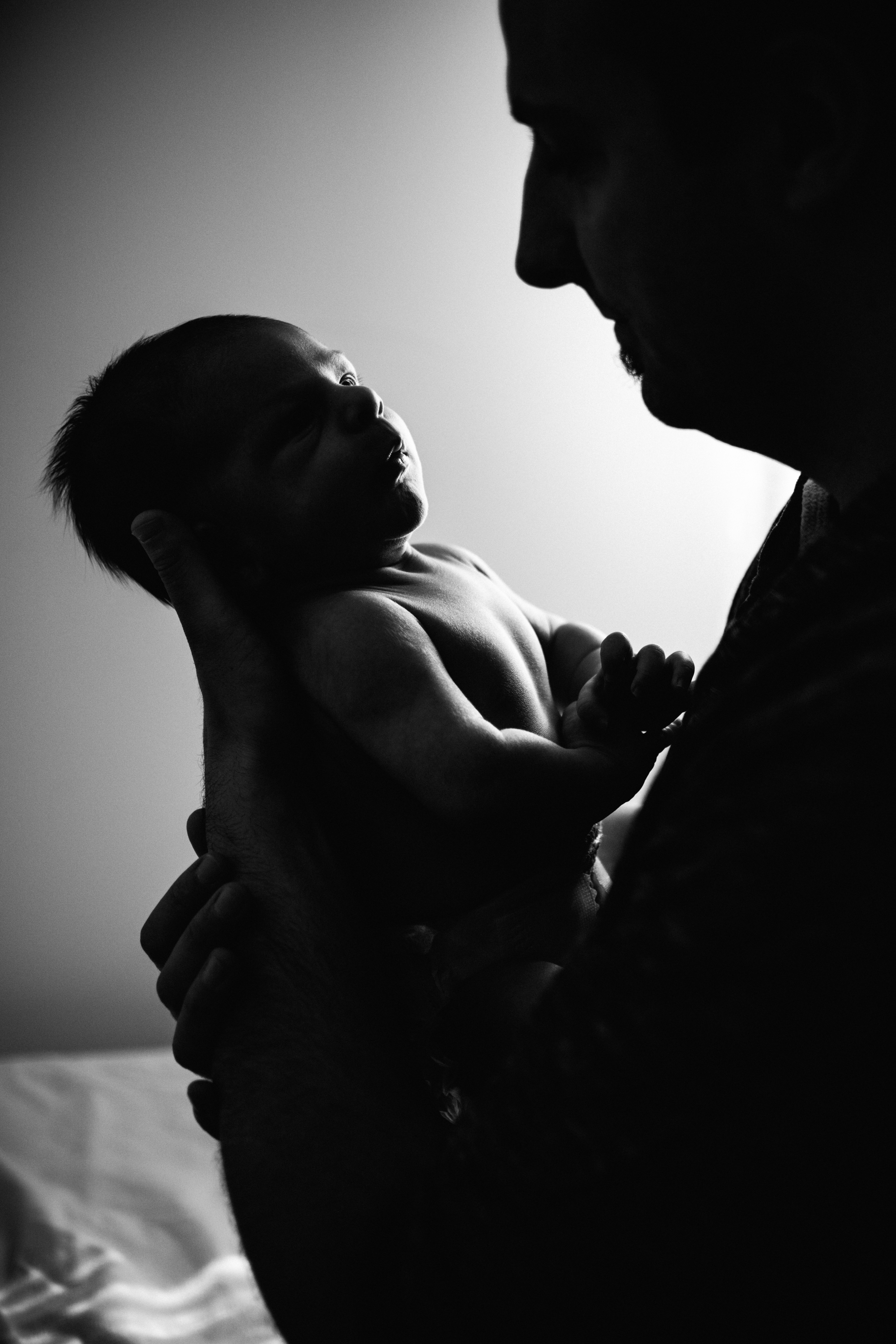 photo-noir-et-blanc-d-une-famille-d-un-nouvea-ne-tenu-a-contre-jour-dans-les-mains-de-son-pere-photographe-maternite-bebe-famille-montreal.jpg