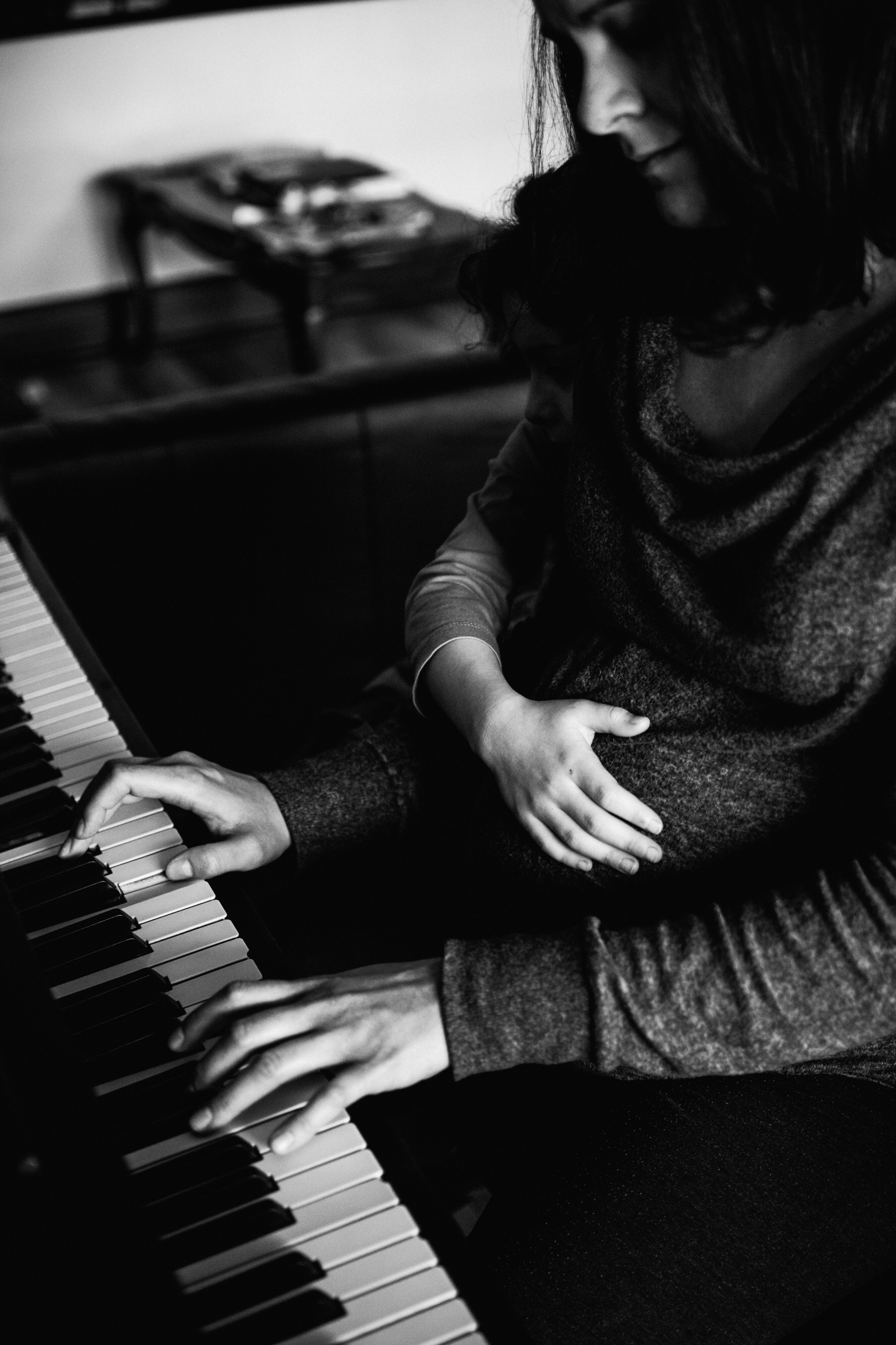 photo-noir-et-blanc-une-femme-enceinte-qui-joue-du-piano-avec-sa-grande-fille-photographe-maternite-bebe-famille-montreal.jpg