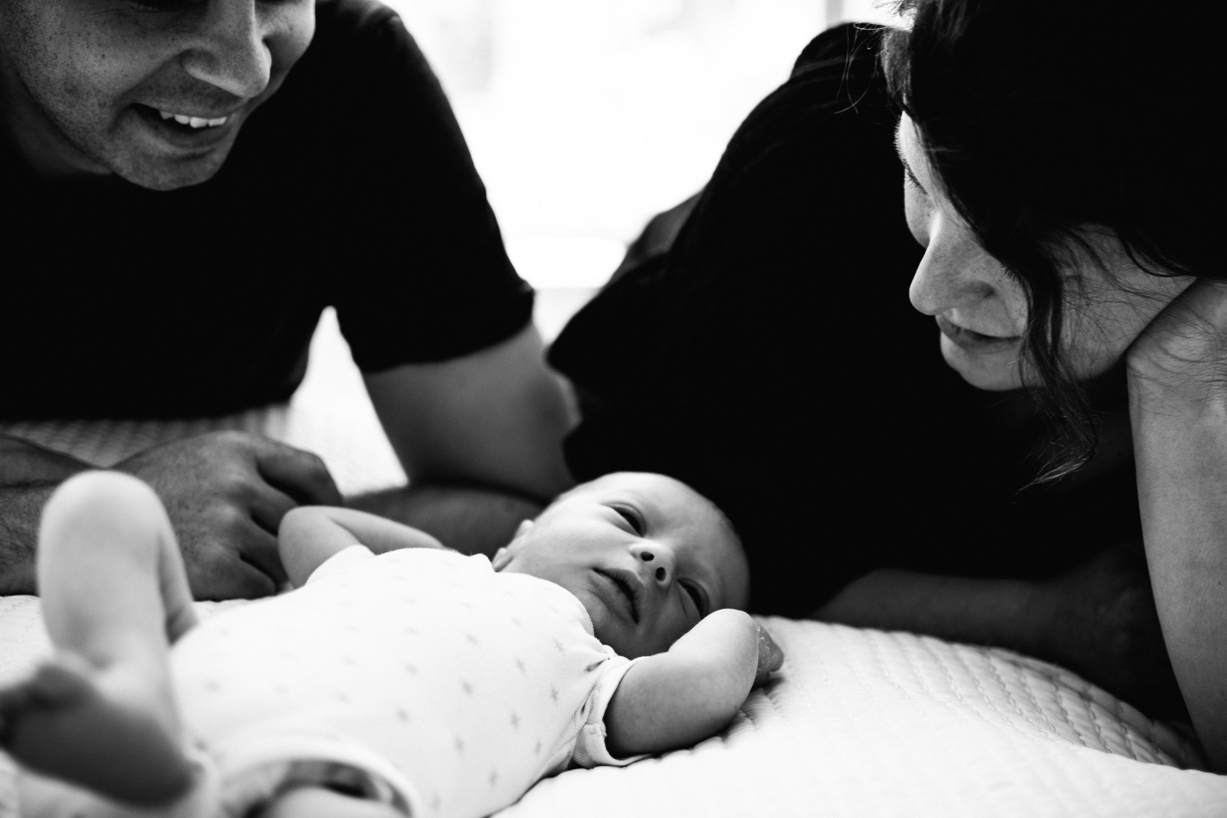 photo-noir-et-blanc-dun-nouveau-ne-et-ses-parents-sur-un-lit_photographe-lifestyle-famille-montreal-4.jpg