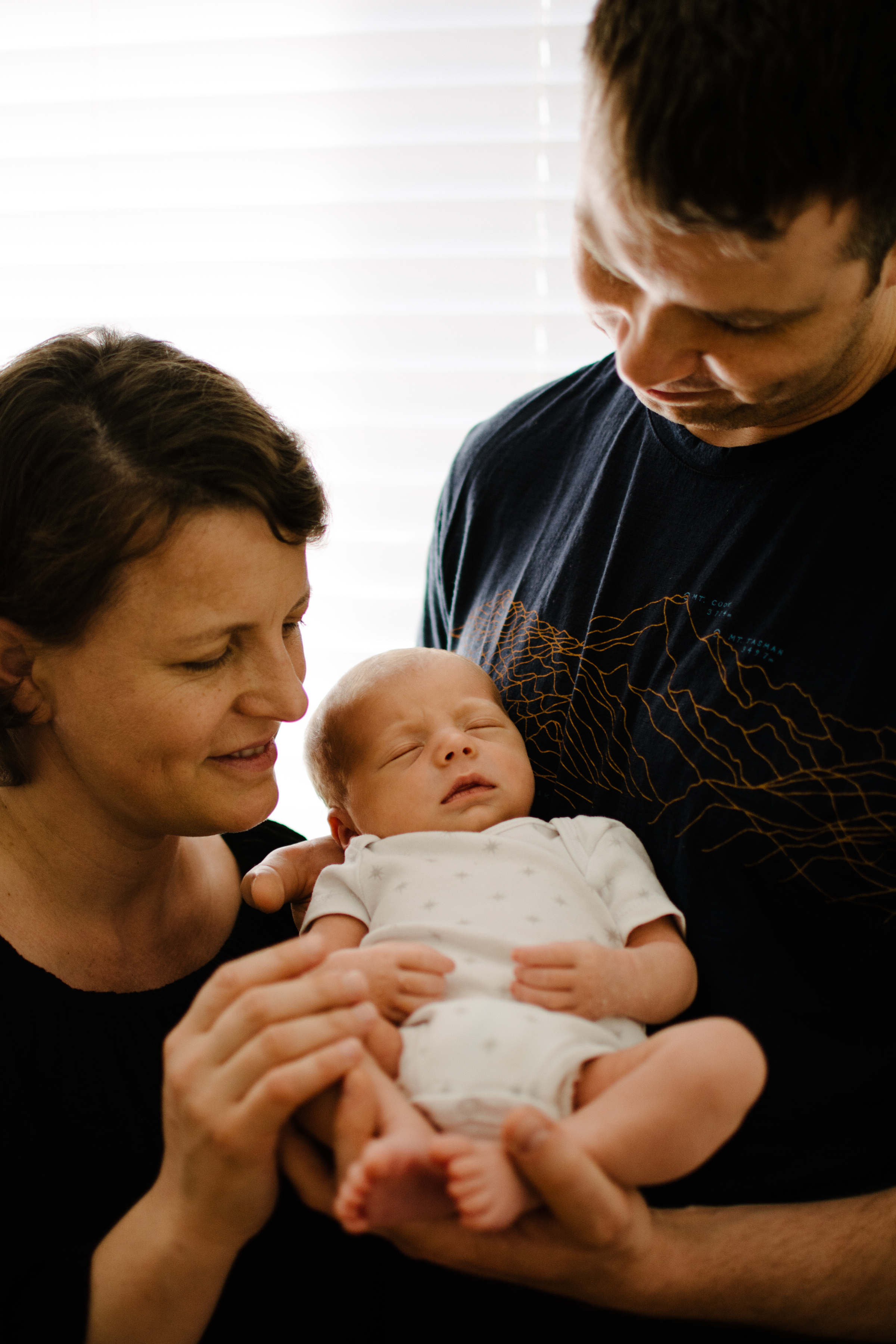 photo-de-parents-admirant-leur-nouveau-ne-dans-la-chambre-de-bebe_photographe-lifestyle-famille-montreal.jpg