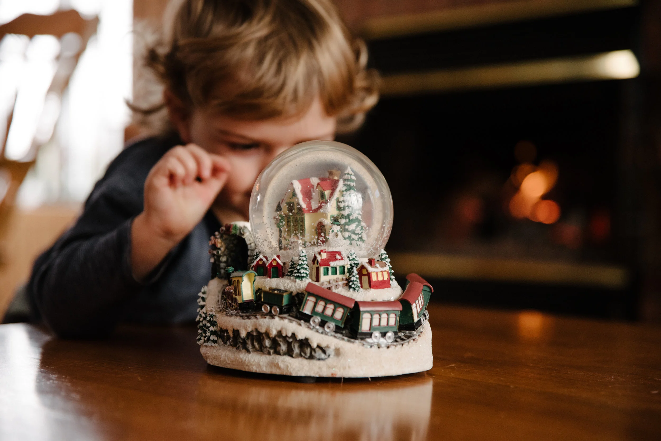 024_photo-d-un-enfant-qui-observe-une-boule-de-neige-de-noel-devant-un-feu-de-foyer-photographe-lifestyle-famille-enfant-a-montreal-035.jpg