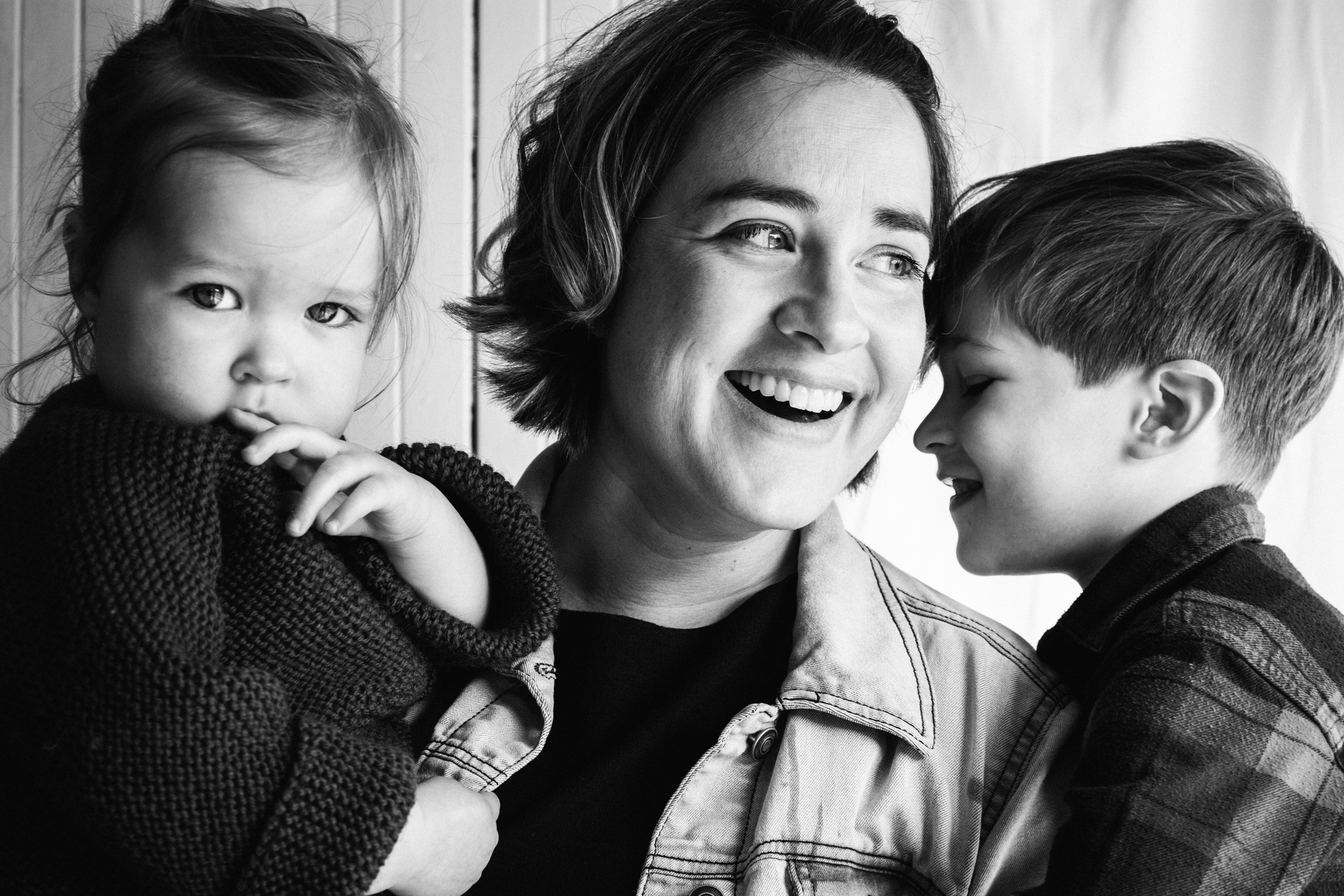 photo-noir-et-blanc-d-une-mere-souriante-avec-ses-deux-enfants-dans-les-bras-photographe-famille-a-montreal-cadeau-fete-des-meres-14.jpg
