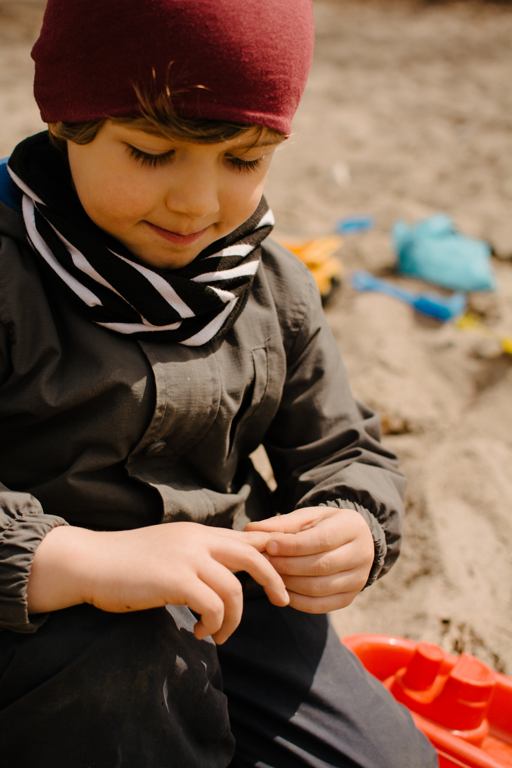 photo-enfant-qui-se-tient-le-doigt-carre-de-sable-photographe-documentaire-famille-lifestyle-a-montreal-1.jpg