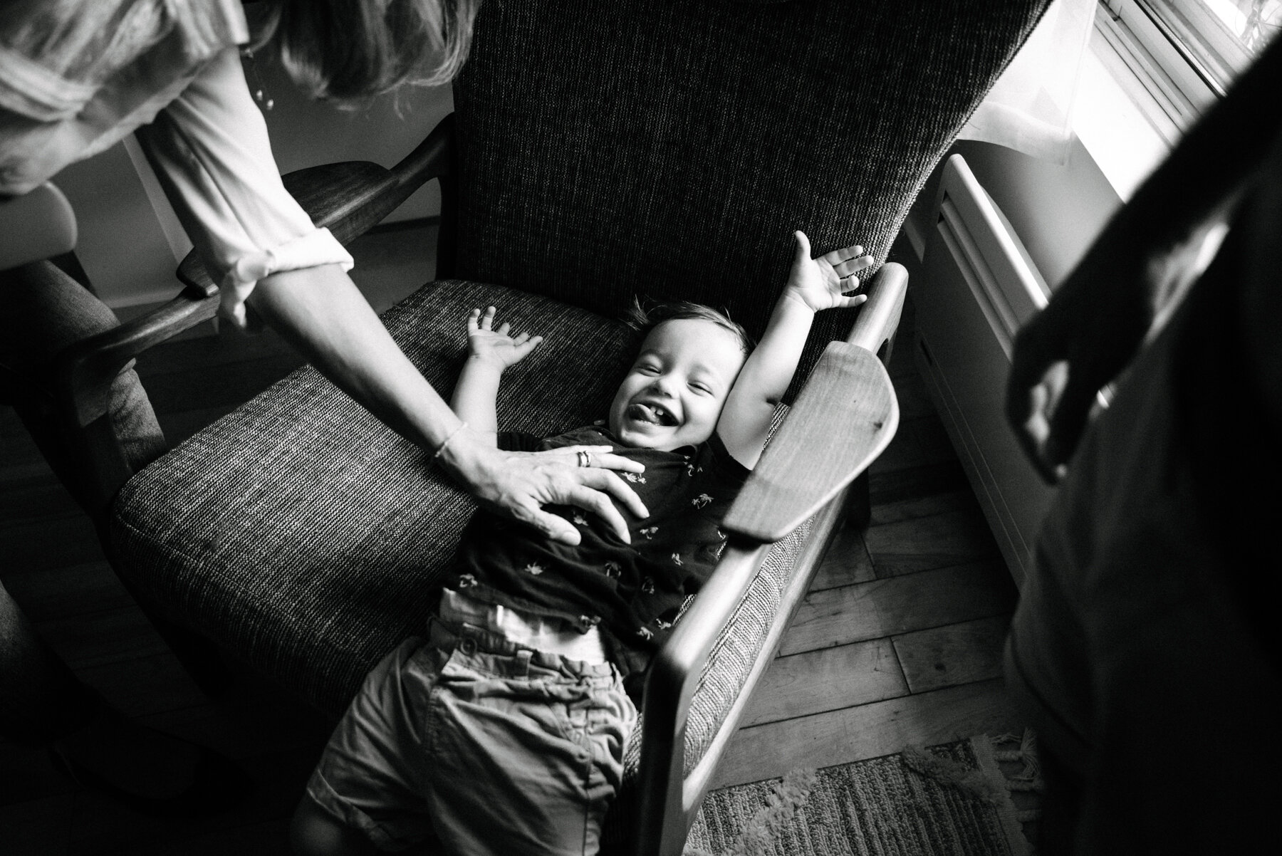 011photo-noir-et-blanc-enfant-qui-rigole-et-se-fait-chatouiller-couche-sur-un-fauteuil-photographe-de-famille-a-montreal-marianne-charland-024.jpg
