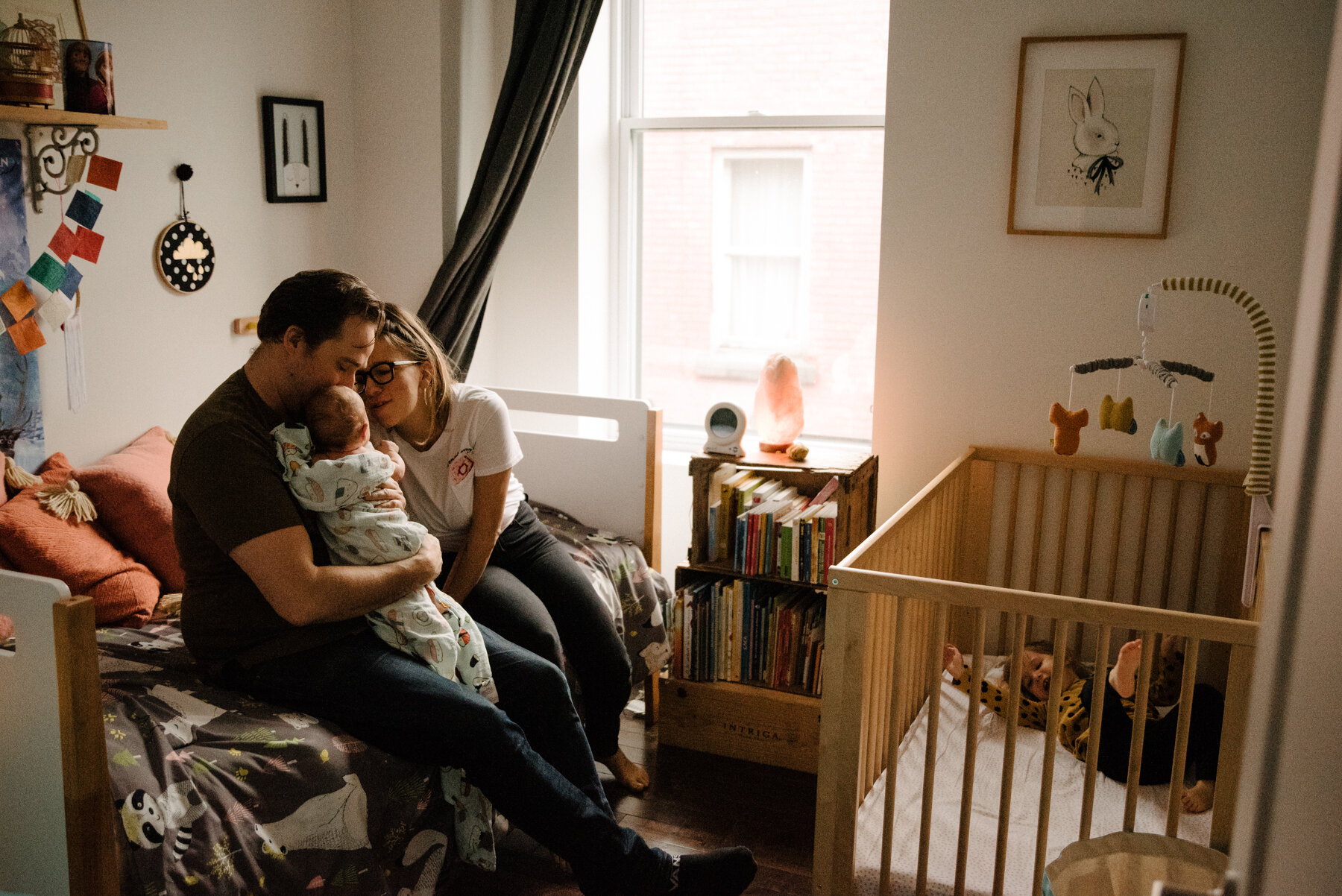 015photo-parents-et-bebe-sur-le-lit-pendant-que-grande-soeur-est-dans-la-bassinette-photographe-de-famille-a-montreal-marianne-charland-055.jpg