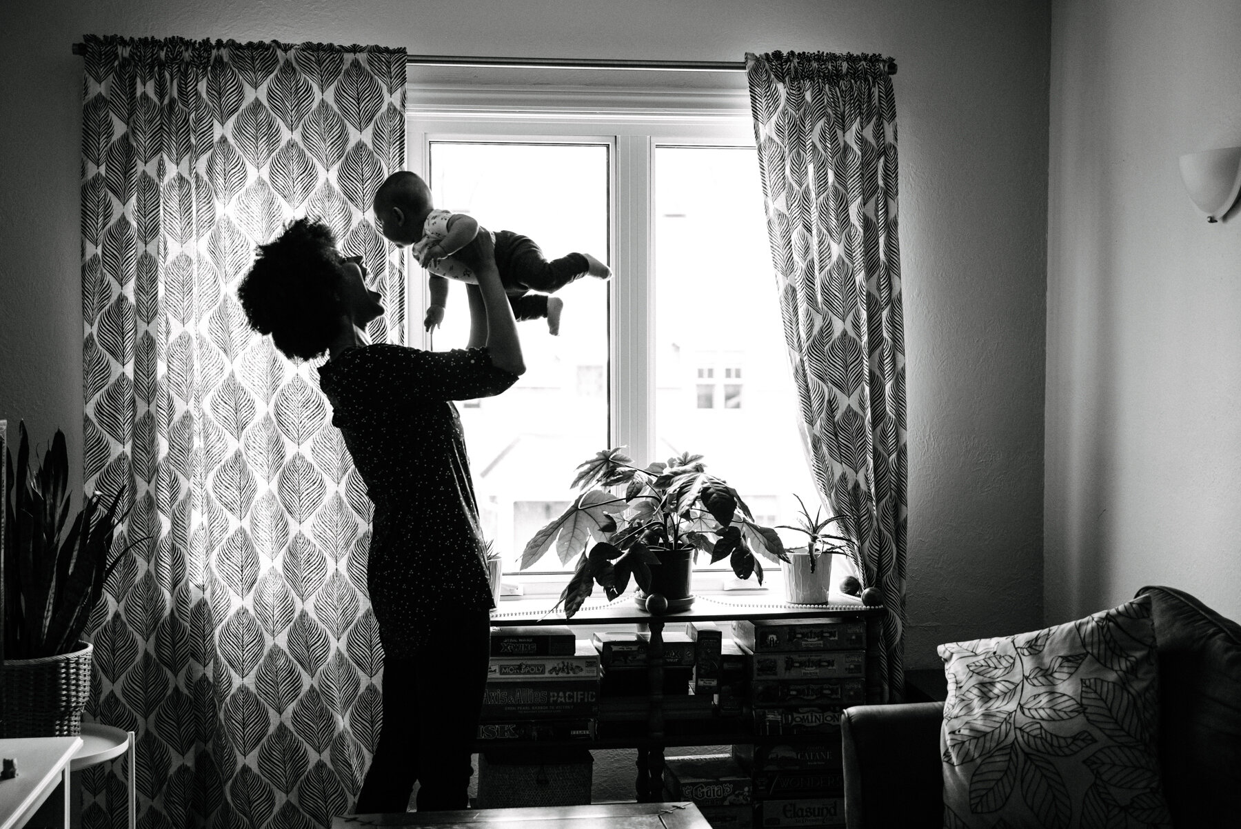 023photo-noir-et-blanc-maman-qui-souleve-son-bebe-dans-les-airs-devant-une-grande-fenetre-photographe-de-famille-a-montreal-marianne-charland-266.jpg