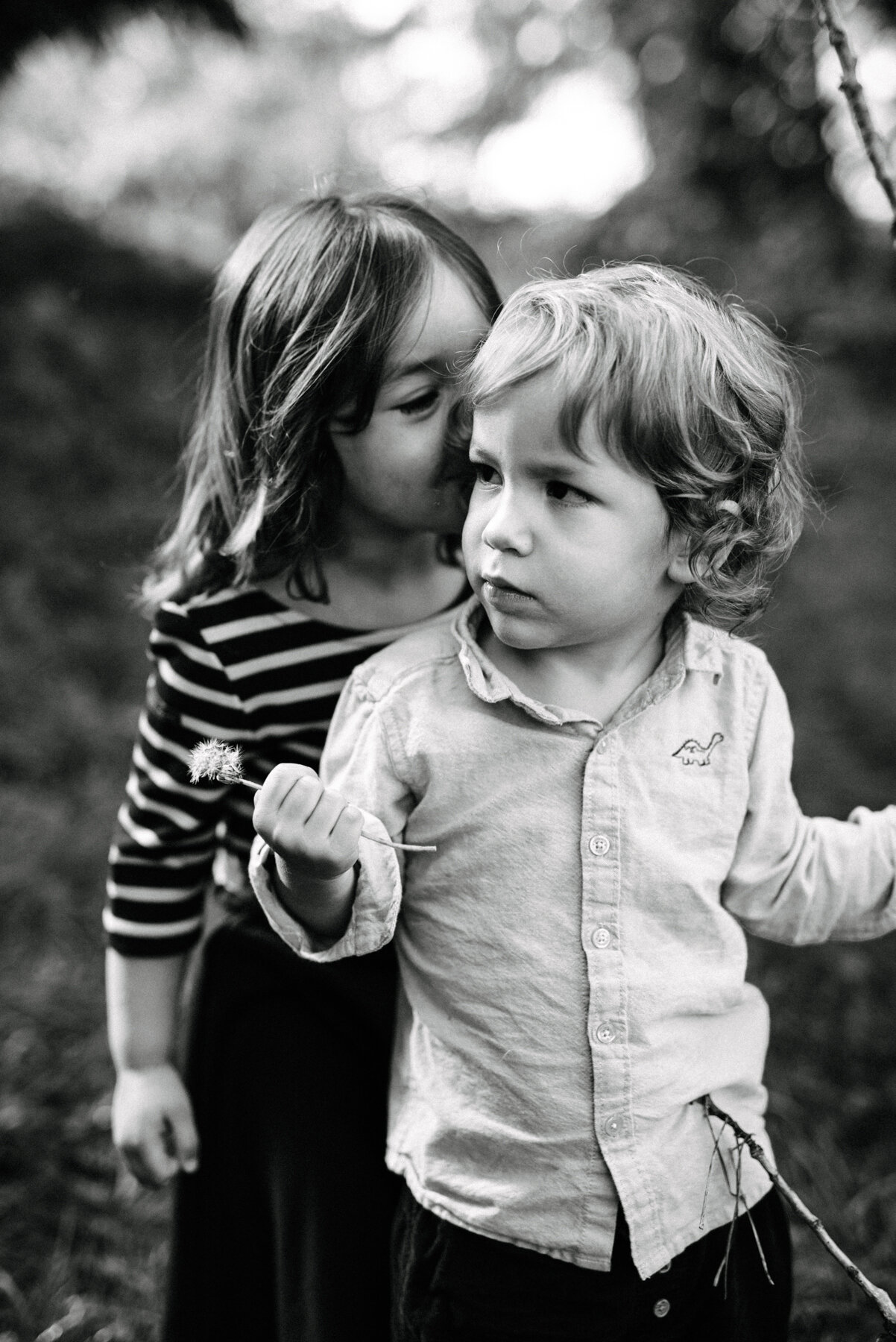 057photo-noir-et-blanc-grande-soeur-taquine-qui-embrasse-son-petit-frere-par-derriere-dans-un-parc-photographe-de-famille-a-montreal-marianne-charland-599.jpg
