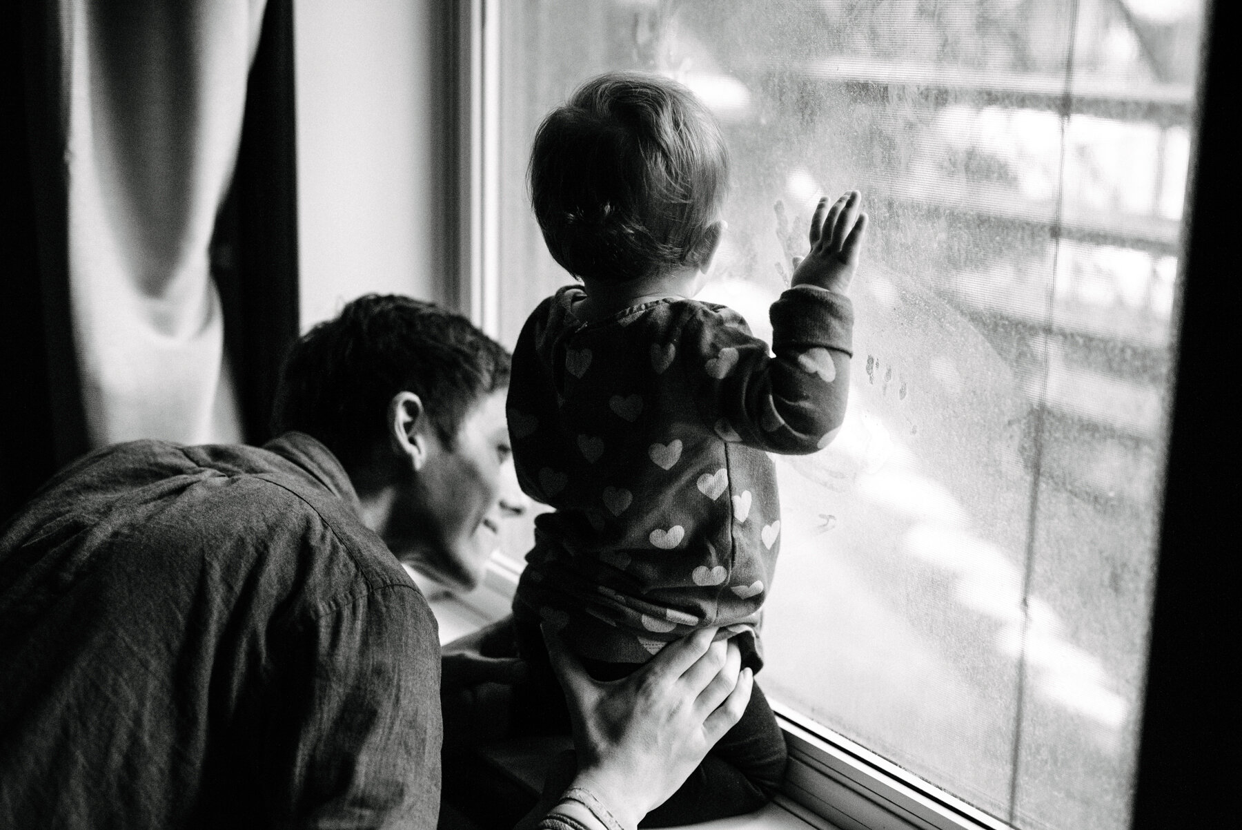 061photo-noir-et-blanc-bambine-qui-regarde-par-la-fenetre-a-genoux-sur-le-rebord-avec-son-pere-photographe-de-famille-a-montreal-marianne-charland-275.jpg