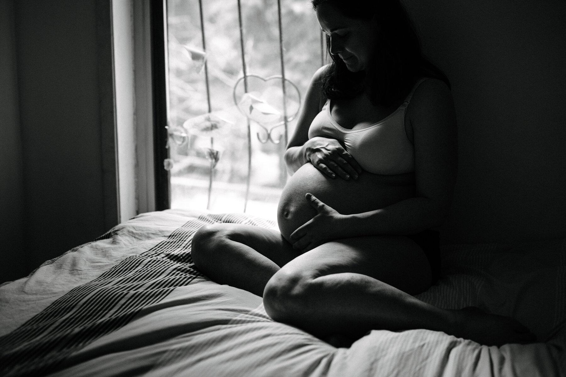 013photo-noir-et-blanc-femme-enceinte-souriante-assise-sur-un-lit-pres-d-une-fenetre-photographe-lifestyle-de-maternite-a-montreal-marianne-charland-215.jpg