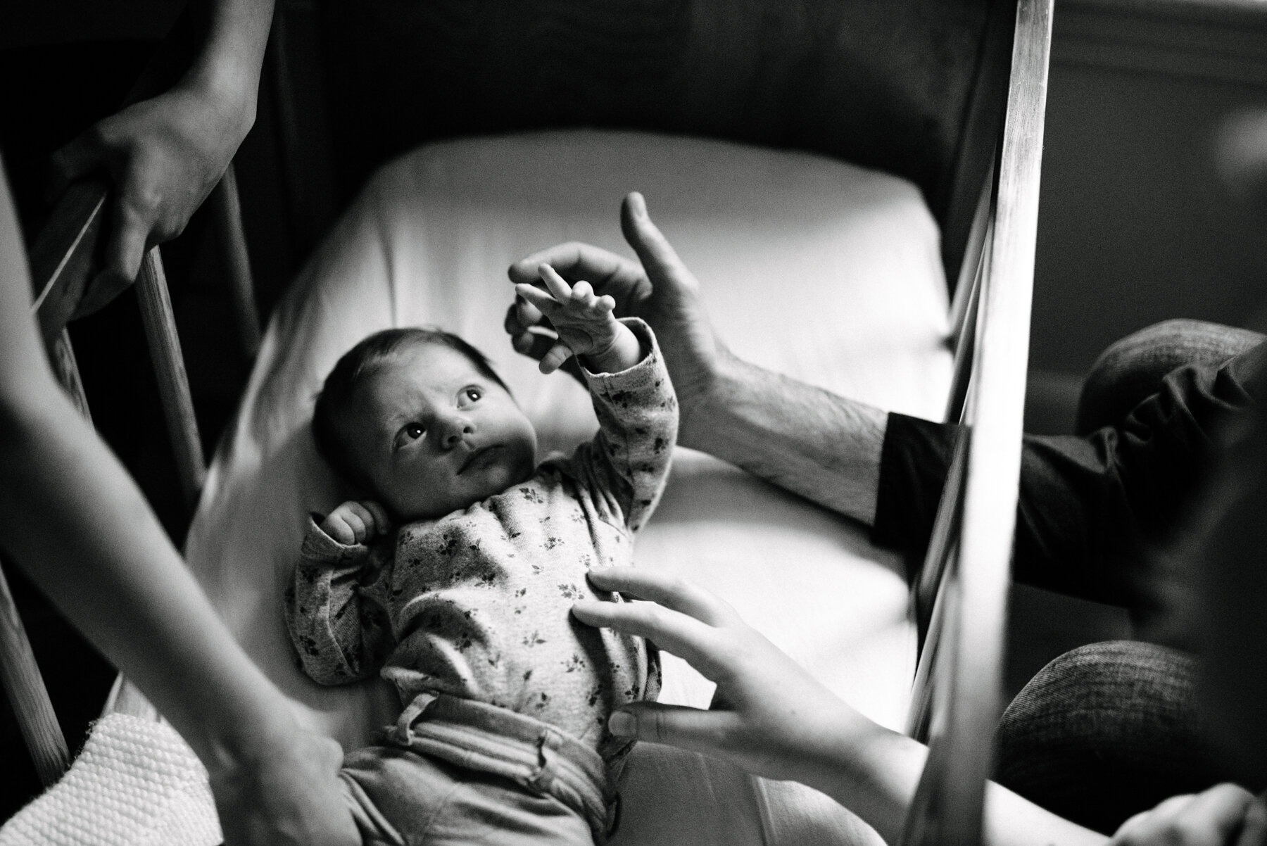 021photo-noir-et-blanc-bebe-couche-dans-bassinette-et-famille-qui-le-touche-photographe-de-nouveau-ne-a-montreal-marianne-charland-325.jpg