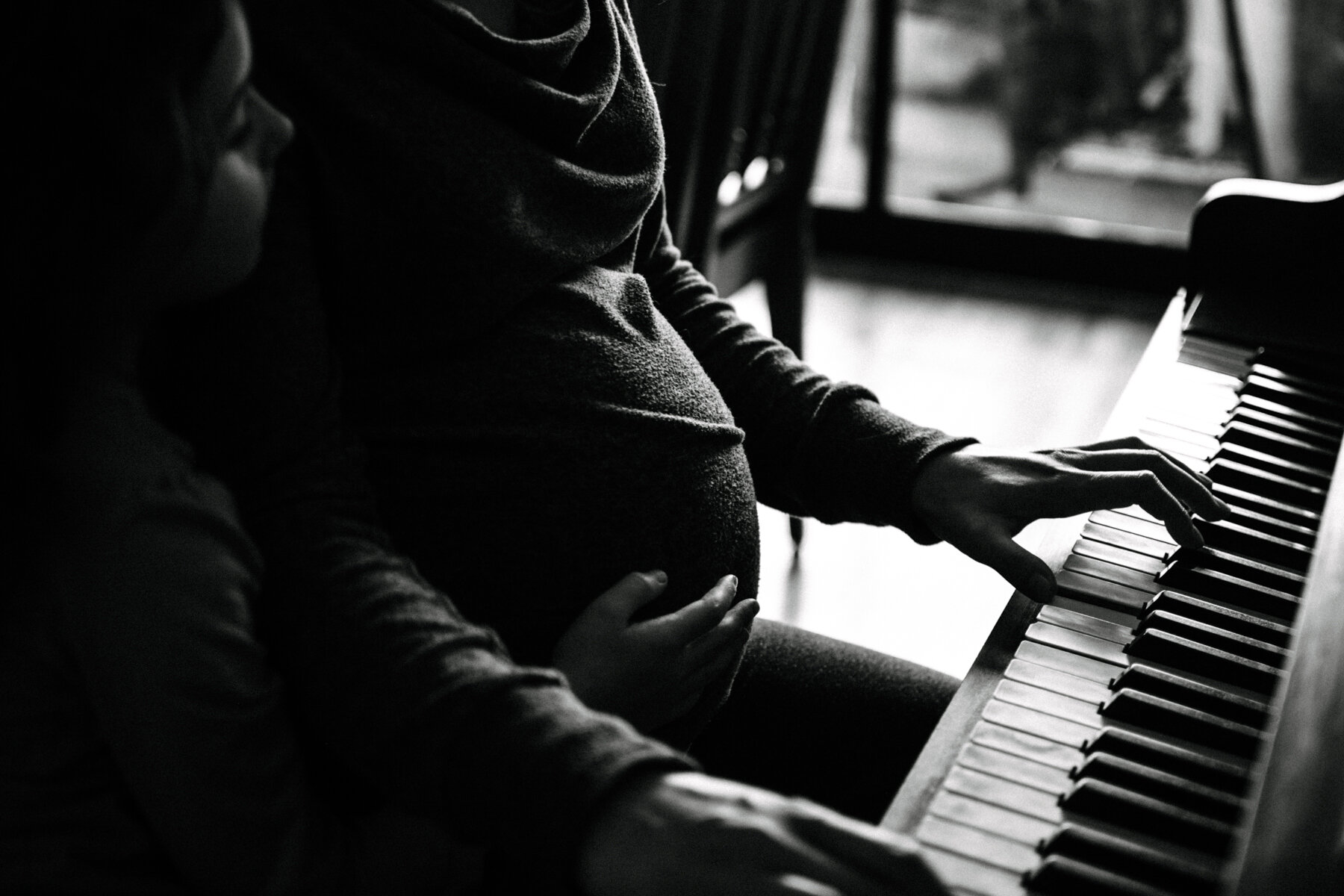 051photo-noir-et-blanc-femme-enceinte-qui-joue-du-piano-grande-soeur-touche-au-ventre-photographe-de-maternite-nouveau-ne-a-montreal-marianne-charland-70.jpg