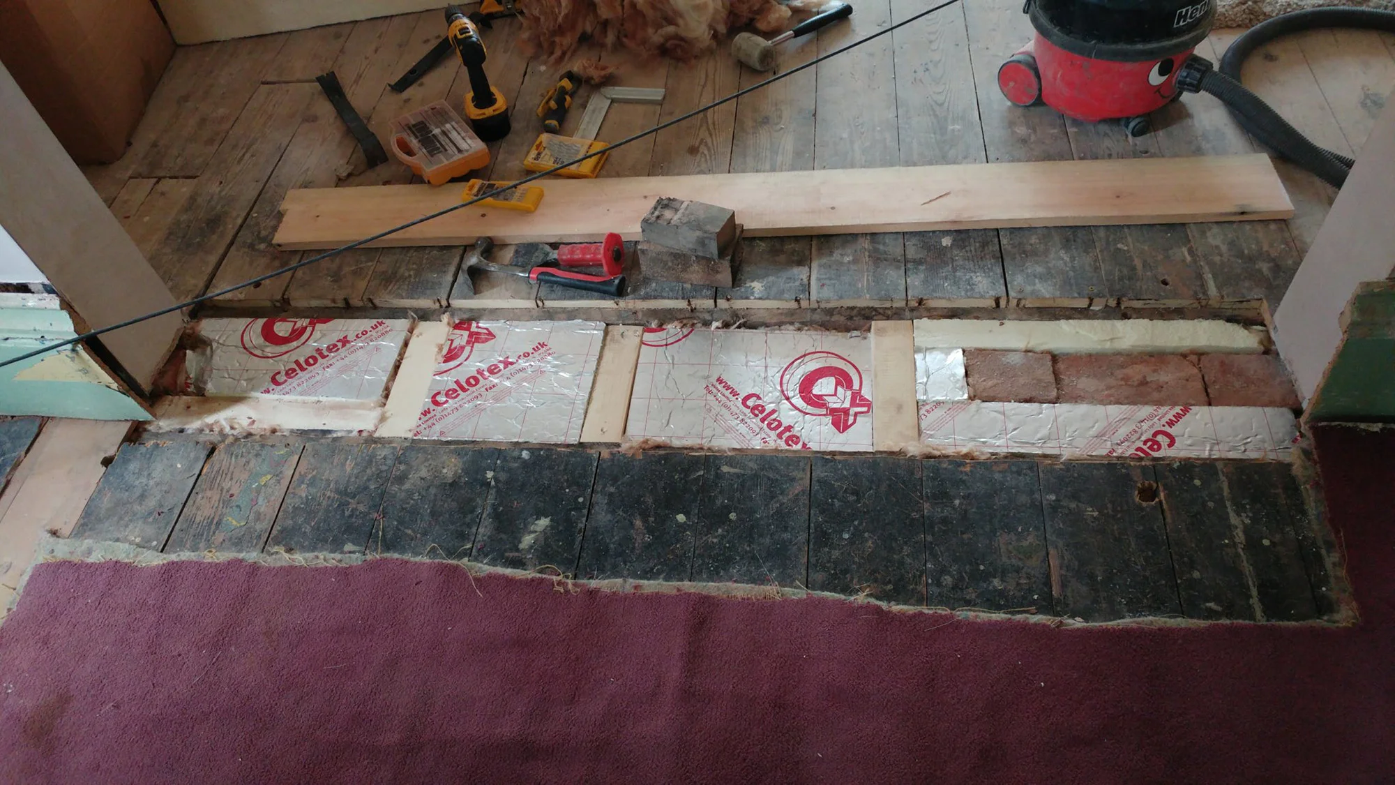 Inserting a jigsaw of insulation board pieces and rockwool into an odd gap between the living room and the dining room. The bricks on the right are part of the wall so we didn’t fancy moving them.