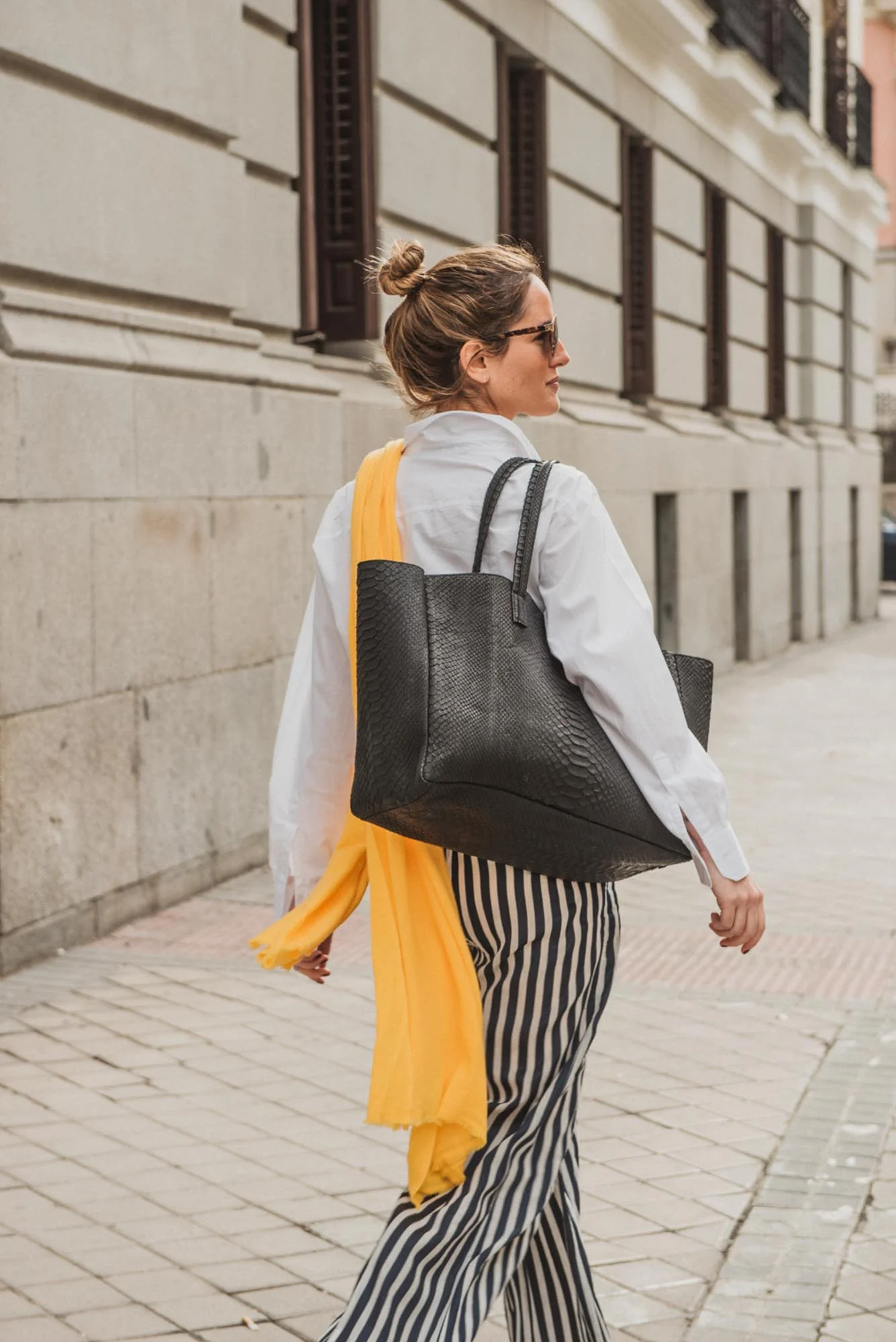 Black python tote bag combined with strap trousers and yellow pashmina