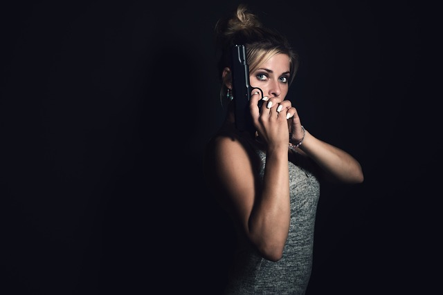 A female with a pistol in her right hand.She is holding the pistol up.