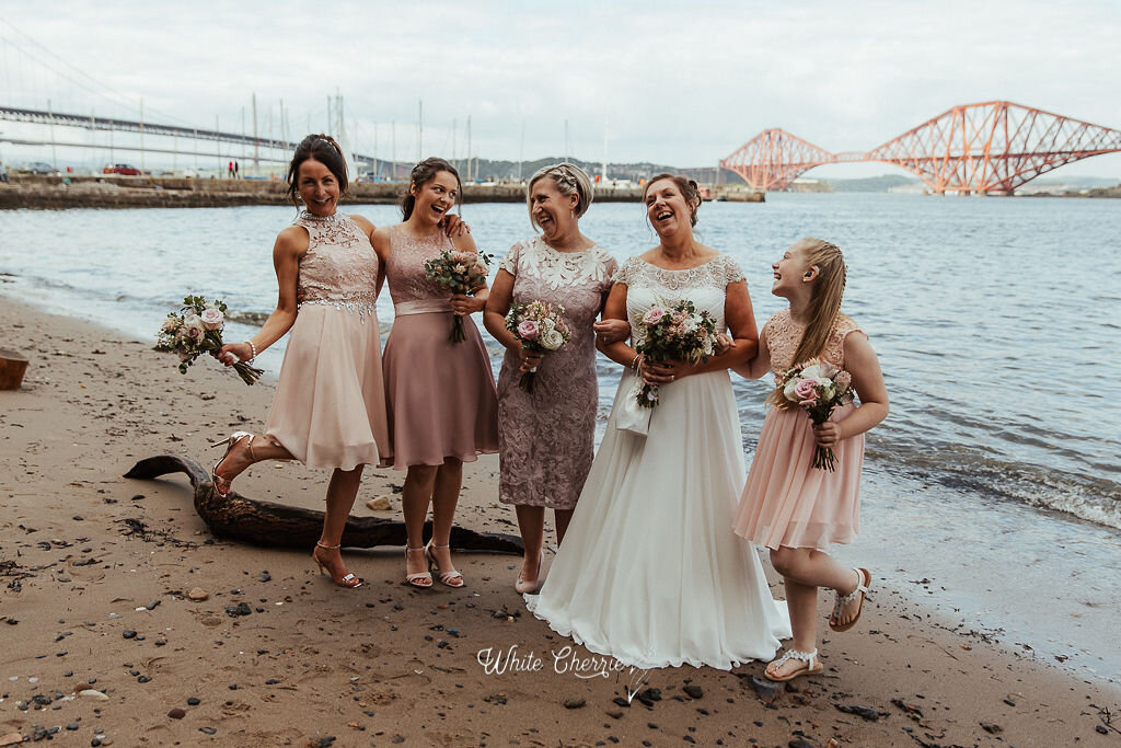 Beautiful Bridesmaid and Bride standing by Forth Bridges holding hand-tied bouquets created by Stunning Flowers, Dunning. 